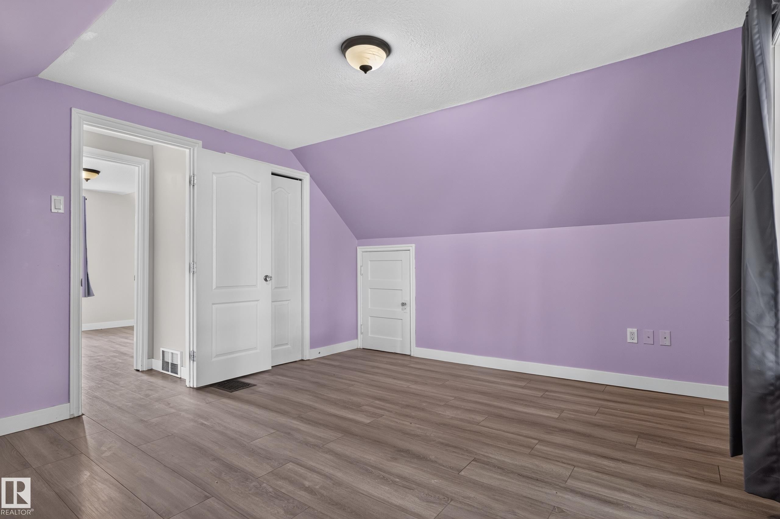 Wood-finish flooring throughout, with a built-in closet featuring white bifold doors - 11549 88 Street Nw, Edmonton, AB - Indoor Photo Showing Other Room