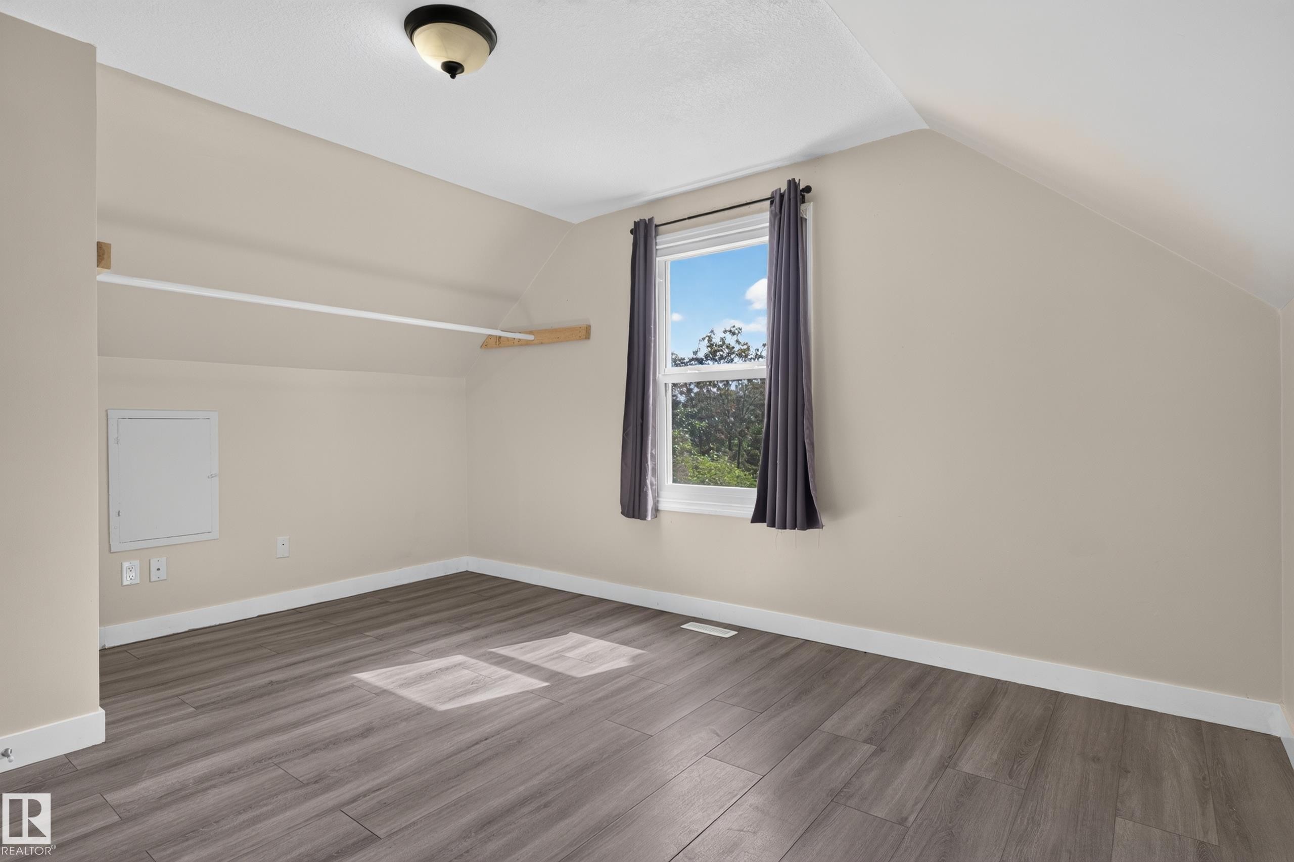 Wood-finish flooring, single window, sloped ceilings, and a built-in hanging rod - 11549 88 Street Nw, Edmonton, AB - Indoor Photo Showing Other Room