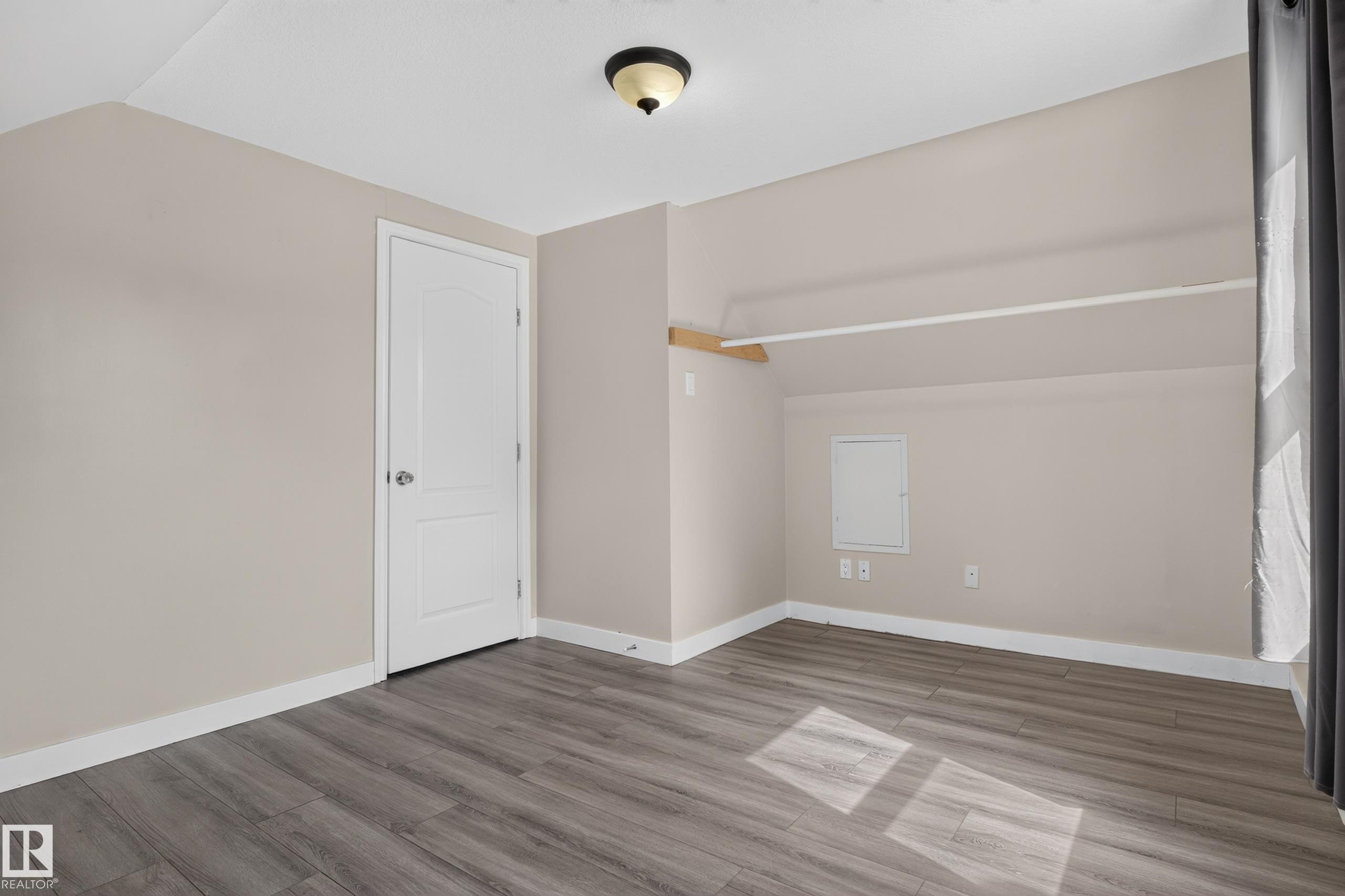 Wood-finish flooring, neutral wall tones, interior door, flush mount ceiling light, and built-in closet shelving - 11549 88 Street Nw, Edmonton, AB - Indoor Photo Showing Other Room
