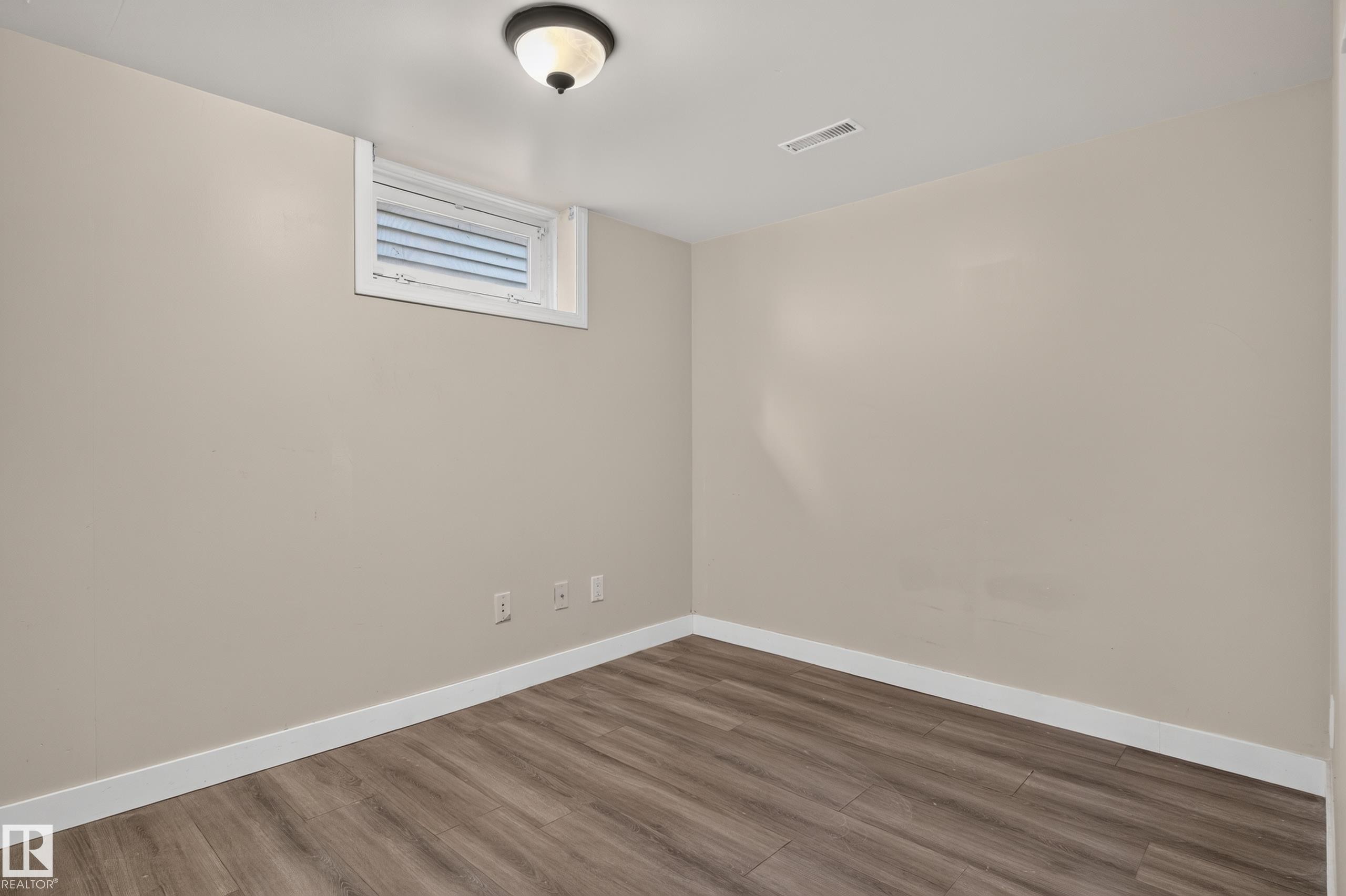 Wood-finish flooring with white trim, a single window with white framing, and a ceiling-mounted light fixture - 11549 88 Street Nw, Edmonton, AB - Indoor Photo Showing Other Room