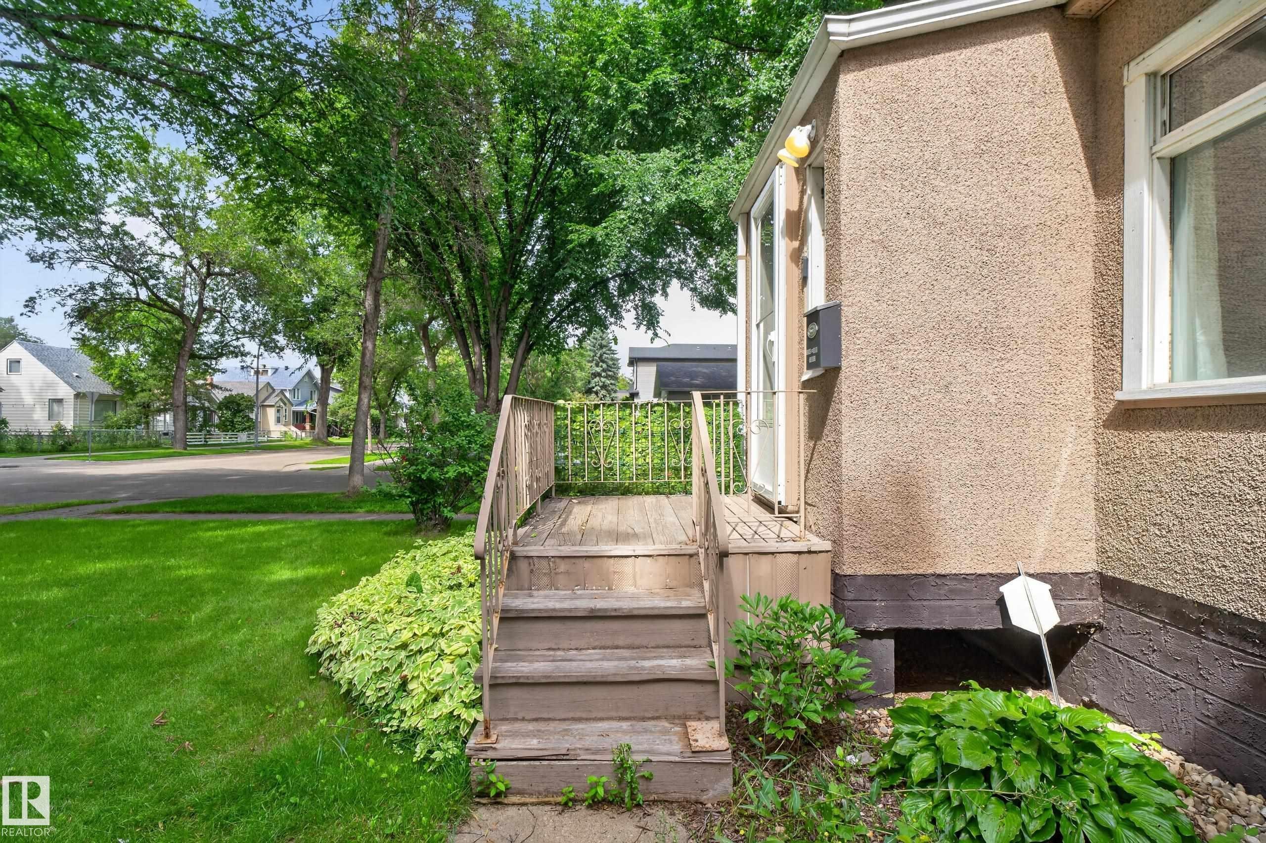 Exterior featuring stucco siding, white-framed windows, and a wooden entry deck with railings - 11549 88 Street Nw, Edmonton, AB - Outdoor With Exterior