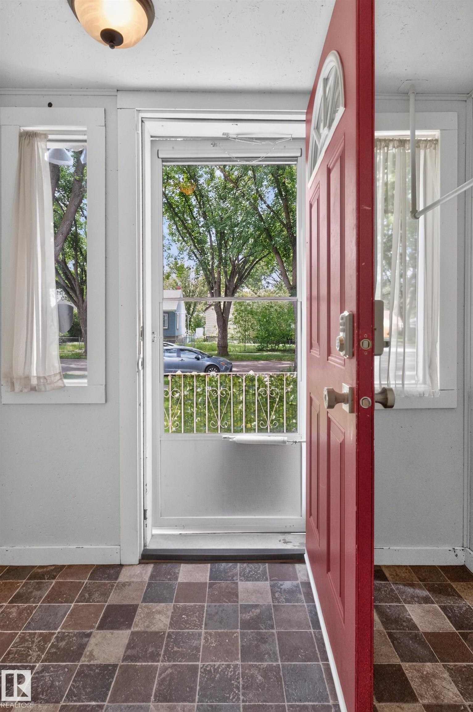 Entryway with checkered tile flooring, a vibrant red entry door with an arched lite, and a flush-mount ceiling light fixture - 11549 88 Street Nw, Edmonton, AB - Indoor Photo Showing Other Room