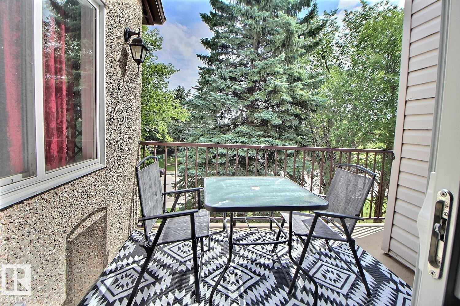 Exterior balcony with metal railing, textured exterior wall, and outdoor wall sconce - #304 14004 26 St Nw, Edmonton, AB - Outdoor With Deck Patio Veranda With Exterior
