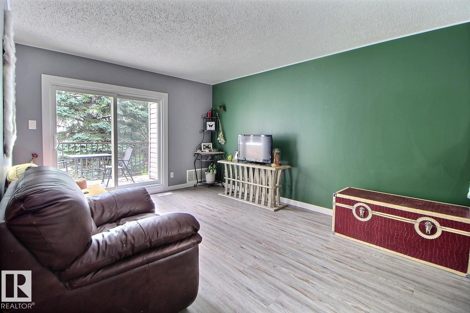 Wood-finish flooring throughout, with a sliding glass door leading to an outdoor balcony - #304 14004 26 St Nw, Edmonton, AB - Indoor