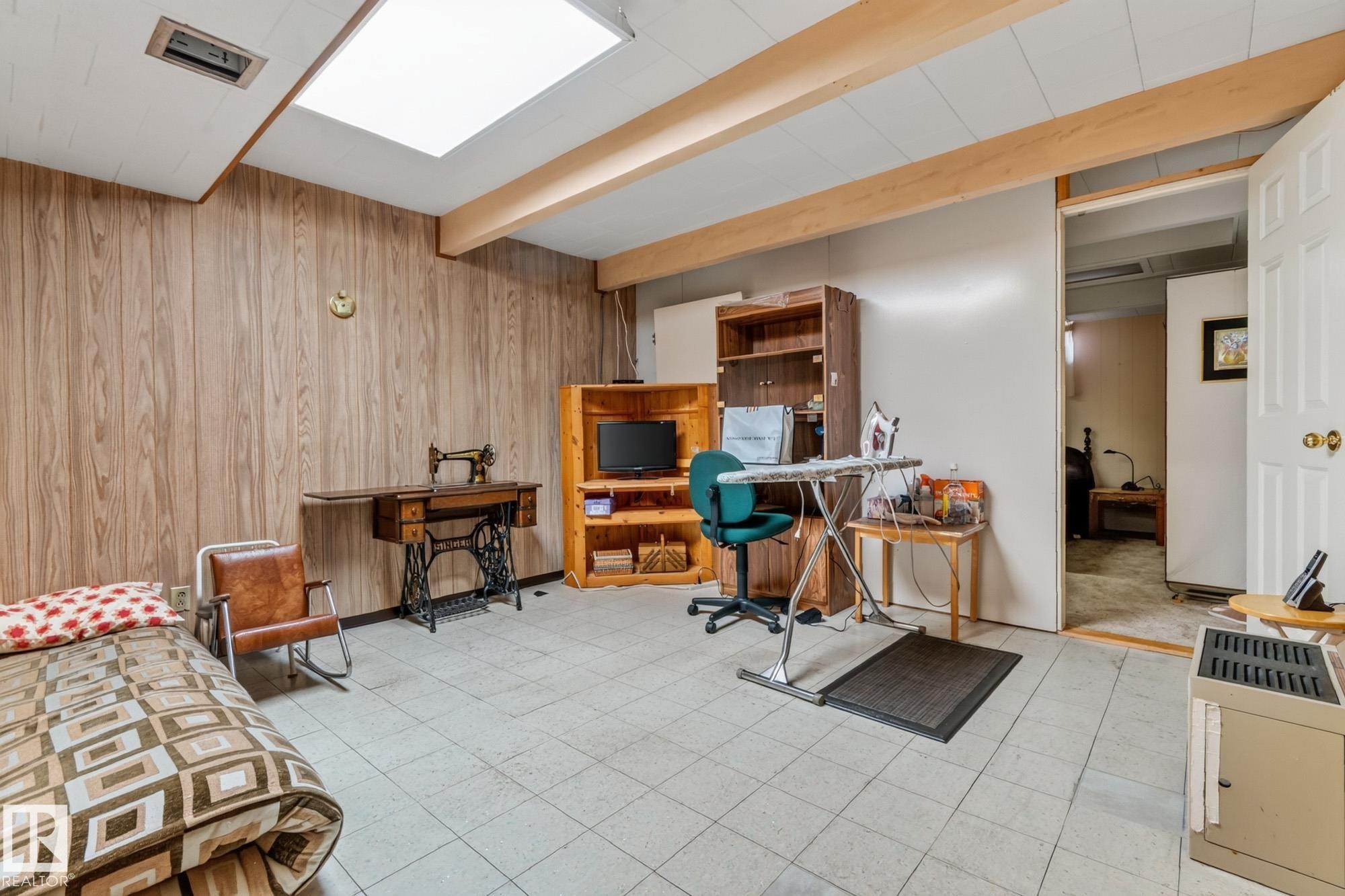 Recessed lighting and a skylight illuminate this versatile space with wood-paneled walls and exposed ceiling beams - 13432 134 Street Nw, Edmonton, AB - Indoor