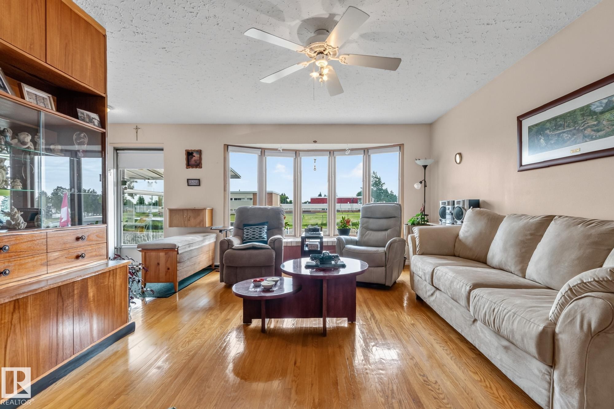 Hardwood flooring, bay window, ceiling fan, built-in cabinetry, and neutral wall tones - 13432 134 Street Nw, Edmonton, AB - Indoor Photo Showing Living Room