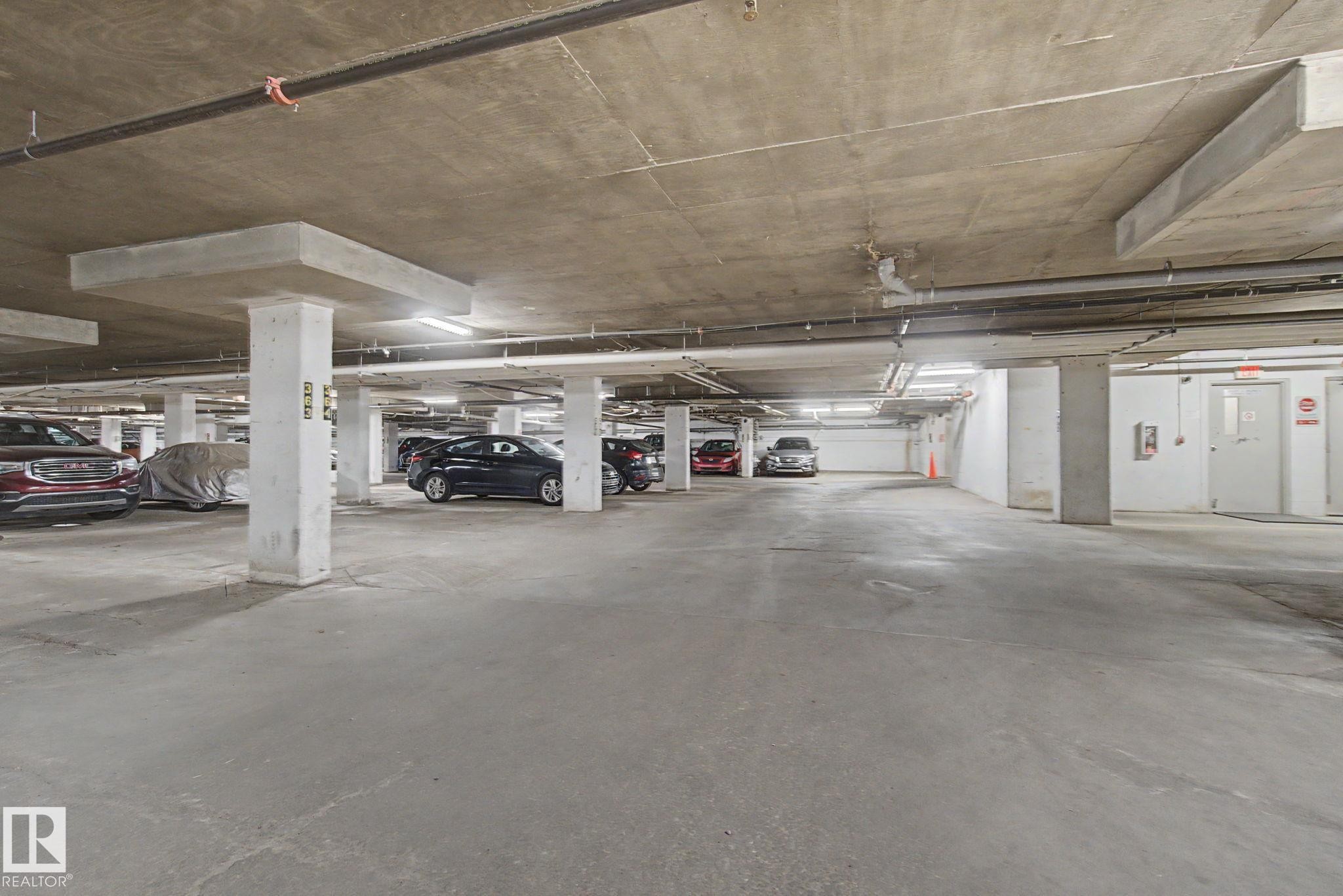 Underground parking garage with concrete flooring, concrete ceiling, and exposed utility piping - #226 17011 67 Av Nw, Edmonton, AB - Indoor Photo Showing Garage