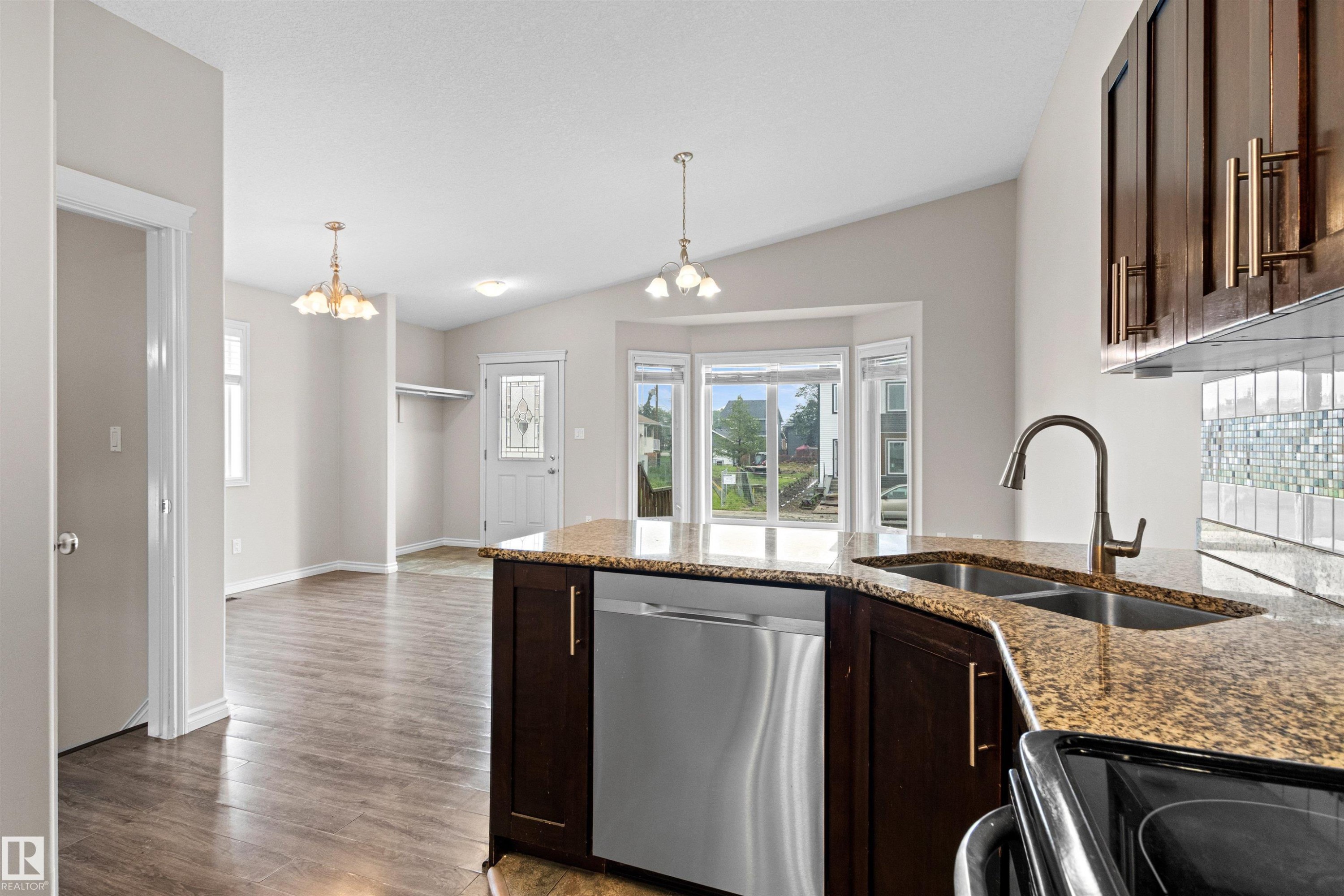 Kitchen island featuring a dual basin sink with a gooseneck faucet, stainless steel dishwasher, and dark wood-finish cabinetry - 10634 155 Street Nw, Edmonton, AB - Indoor Photo Showing Kitchen With Double Sink