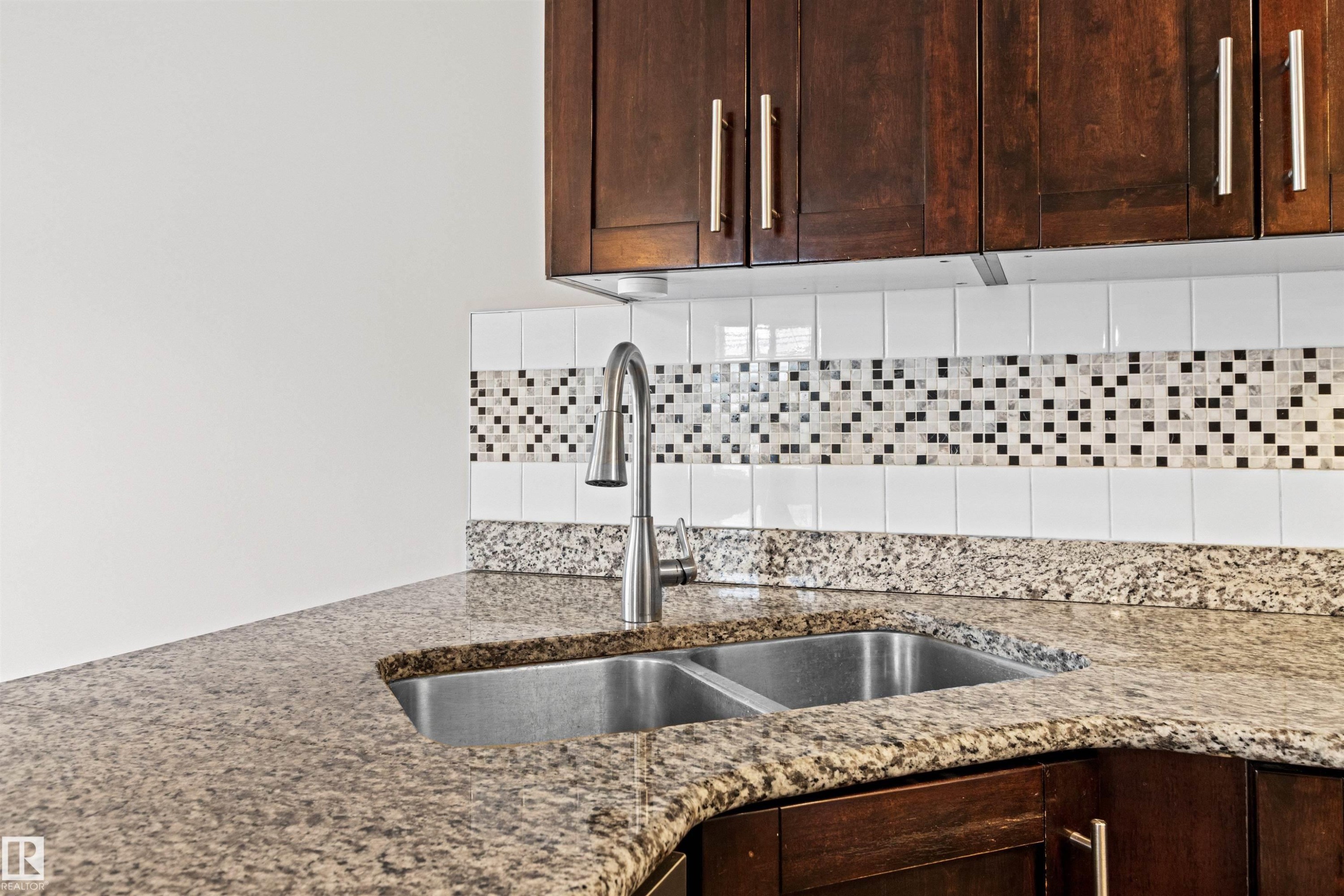 Kitchen sink area featuring a dual stainless steel sink with a gooseneck faucet, granite countertops, and dark wood cabinetry with brushed nickel hardware - 10634 155 Street Nw, Edmonton, AB - Indoor Photo Showing Kitchen With Double Sink