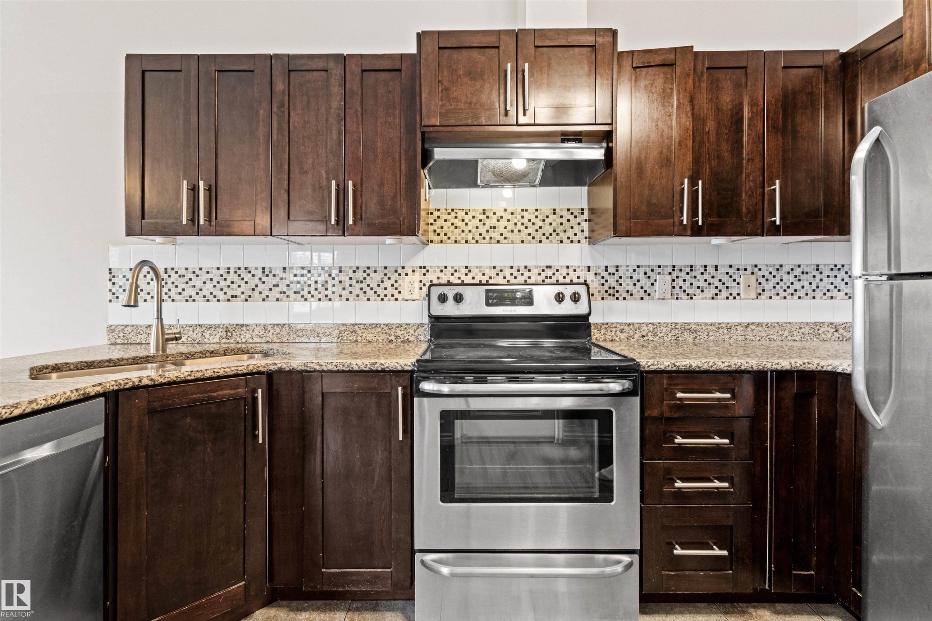 Kitchen featuring dark wood-finish cabinetry, stainless steel appliances, and a mosaic tile backsplash - 10634 155 Street Nw, Edmonton, AB - Indoor Photo Showing Kitchen