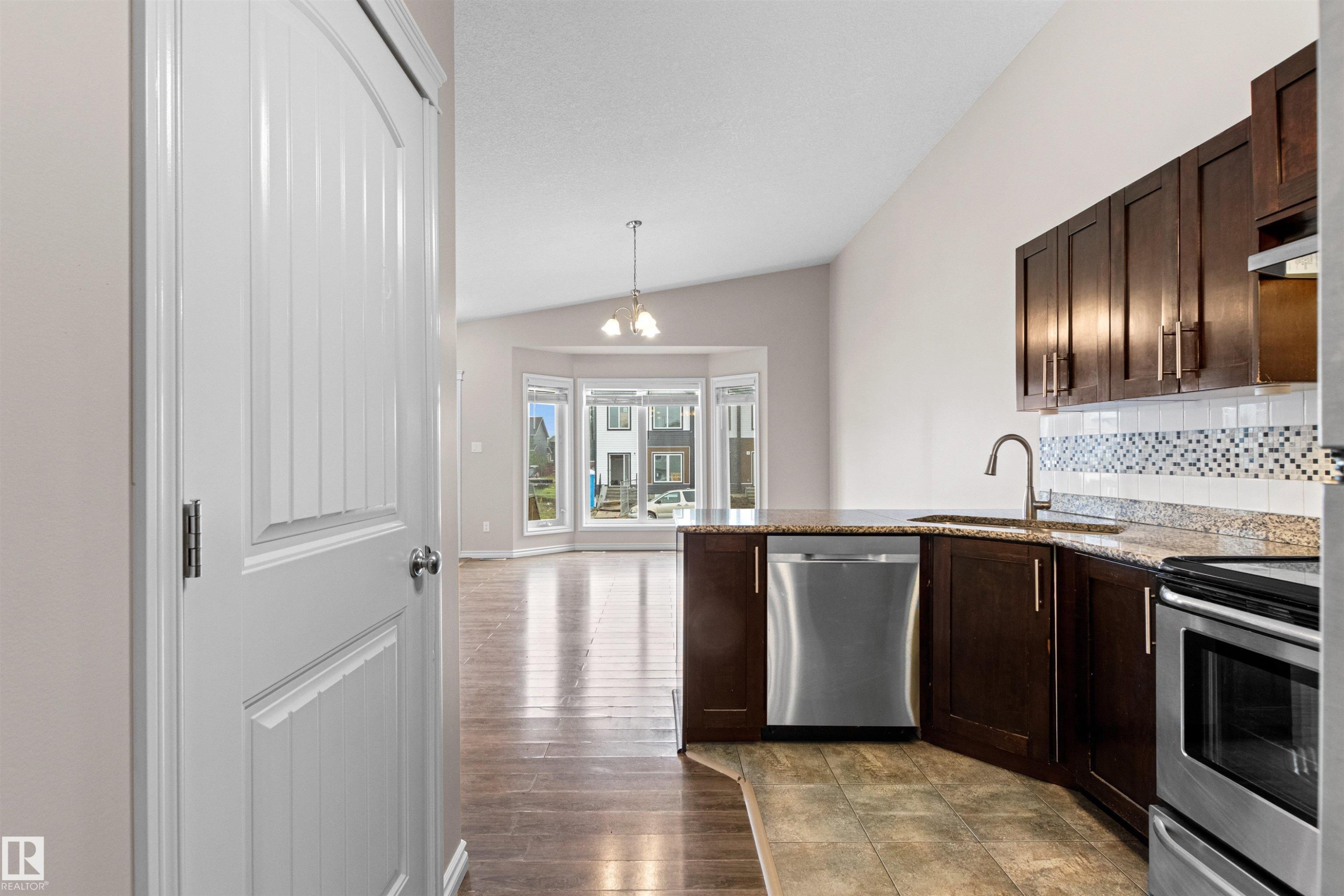 Modern kitchen featuring dark wood cabinetry, stainless steel appliances, granite countertops, and a decorative tile backsplash - 10634 155 Street Nw, Edmonton, AB - Indoor Photo Showing Kitchen