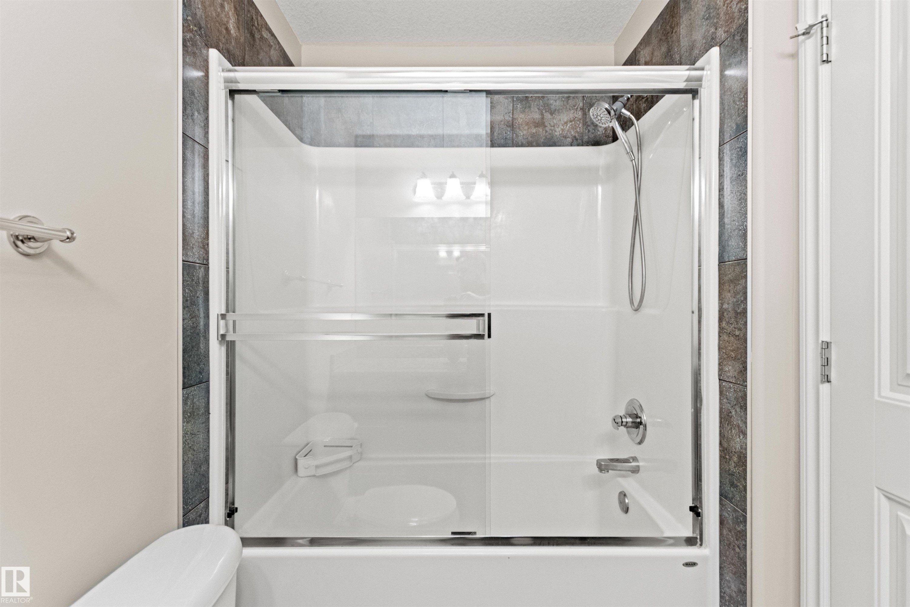 Bathtub shower combination with clear glass enclosure and chrome hardware - 10634 155 Street Nw, Edmonton, AB - Indoor Photo Showing Bathroom