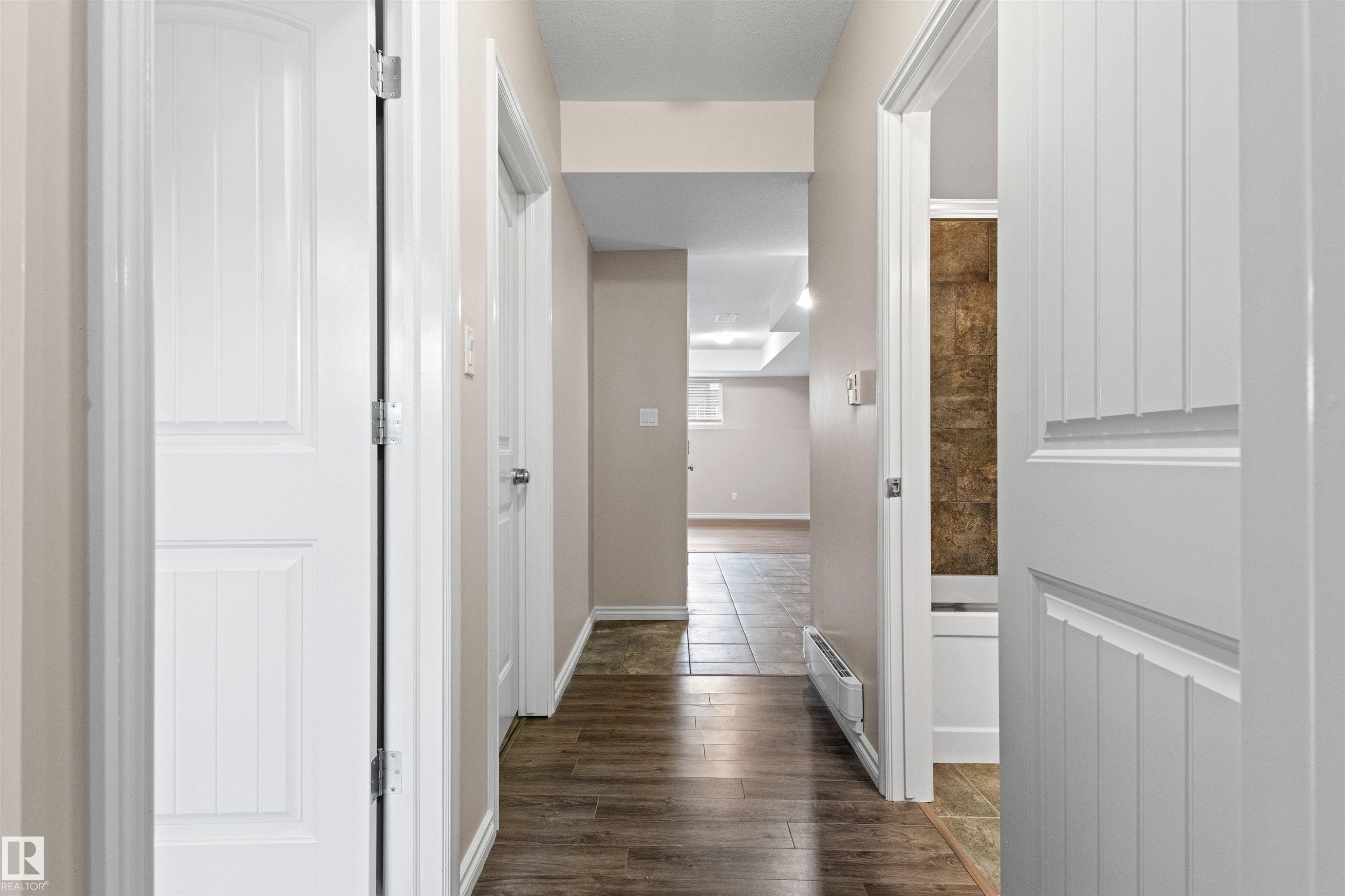 Hallway featuring wood-finish flooring, light neutral wall paint, and white paneled doors - 10634 155 Street Nw, Edmonton, AB - Indoor Photo Showing Other Room
