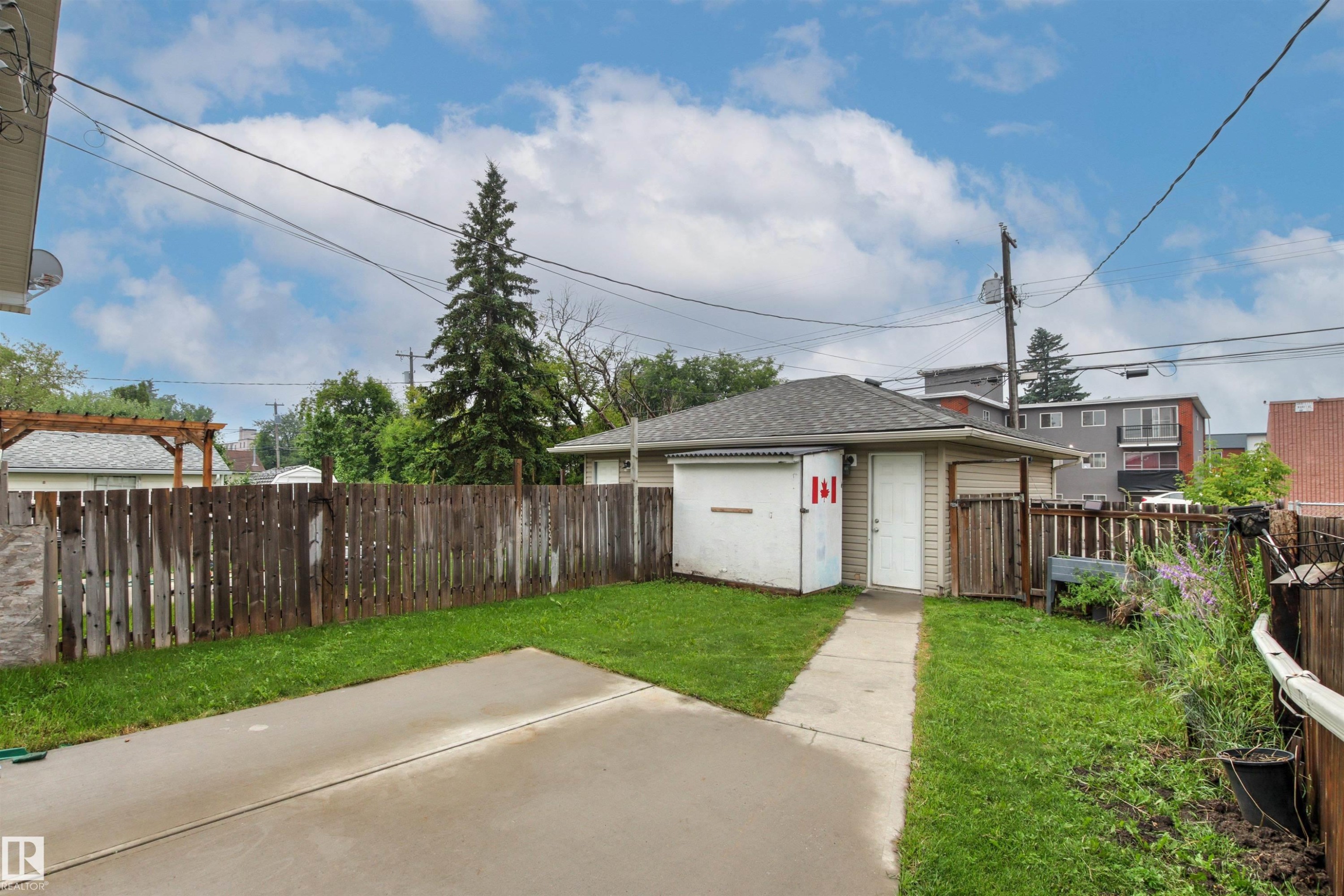 Detached garage with a shingled roof and vinyl siding, featuring a service door and an overhead garage door - 10634 155 Street Nw, Edmonton, AB - Outdoor