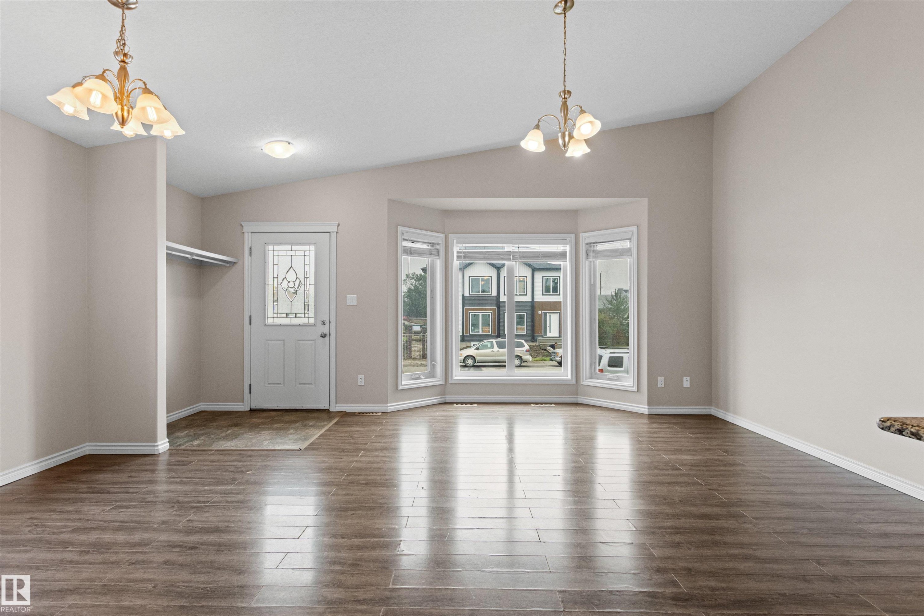 Spacious interior featuring wood-finish flooring, a decorative front entry door with leaded glass, and a prominent bay window - 10634 155 Street Nw, Edmonton, AB - Indoor