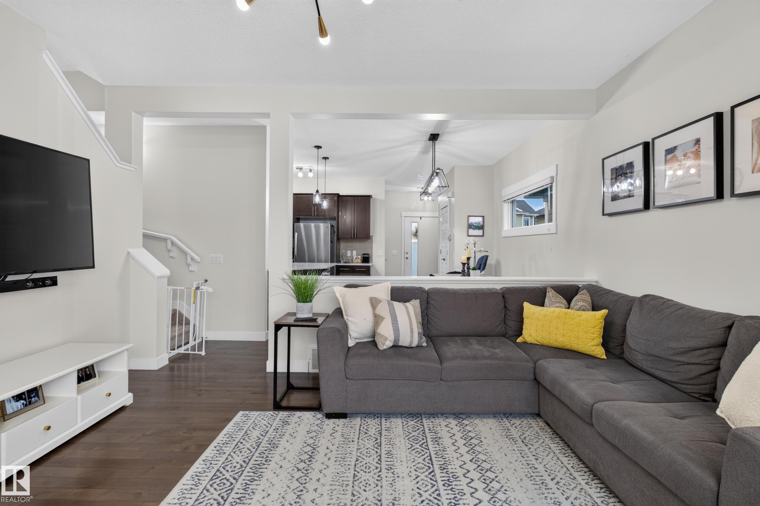 Spacious living area featuring dark wood-finish flooring, light-toned walls, and an open layout to the kitchen - 17305 73 Street Nw, Edmonton, AB - Indoor Photo Showing Living Room