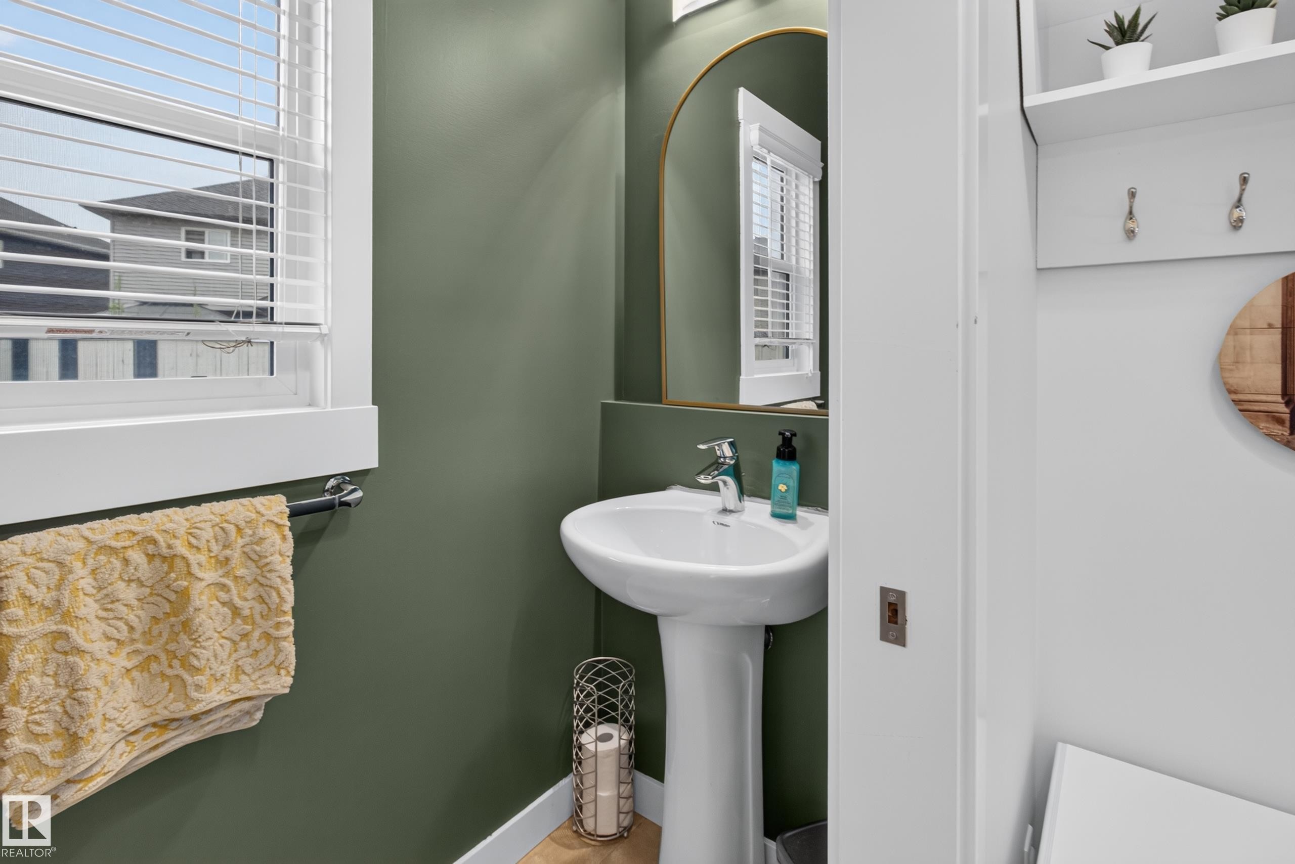 Pedestal sink with a polished chrome faucet set against a green accent wall - 17305 73 Street Nw, Edmonton, AB - Indoor Photo Showing Bathroom