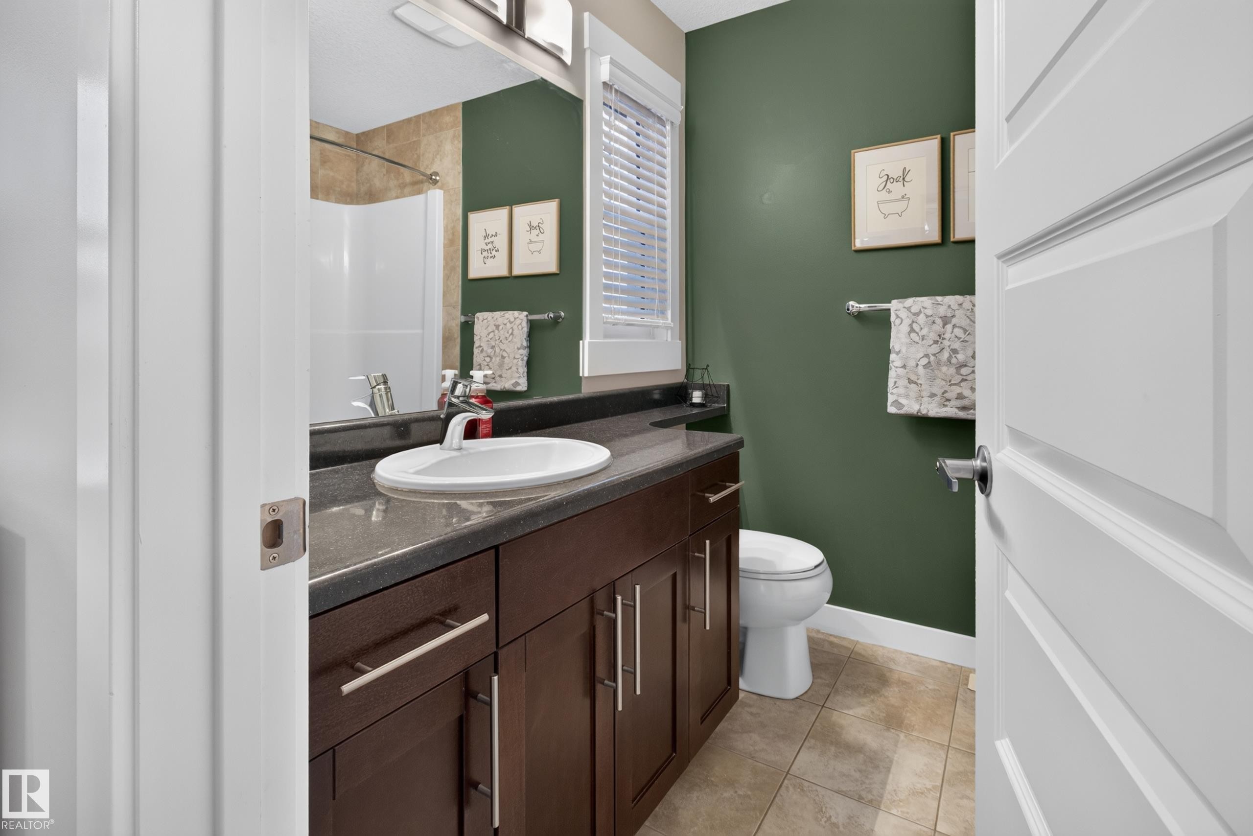 Bathroom featuring a vanity with dark wood-finish cabinetry, a dark countertop, and an undermount sink - 17305 73 Street Nw, Edmonton, AB - Indoor Photo Showing Bathroom