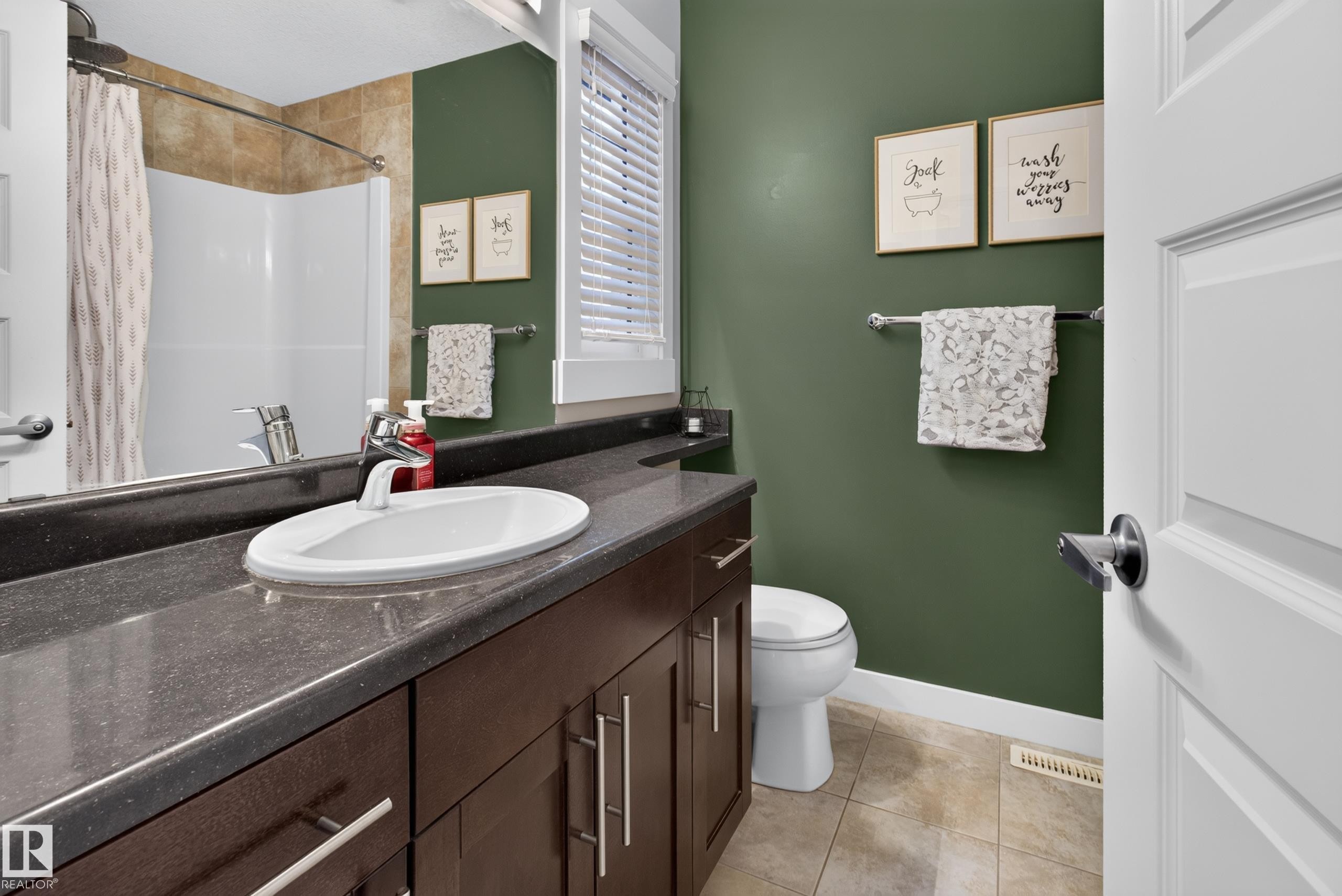 Bathroom featuring a dark wood-finish vanity with an undermount sink, dark stone-finish countertop, and chrome faucet - 17305 73 Street Nw, Edmonton, AB - Indoor Photo Showing Bathroom