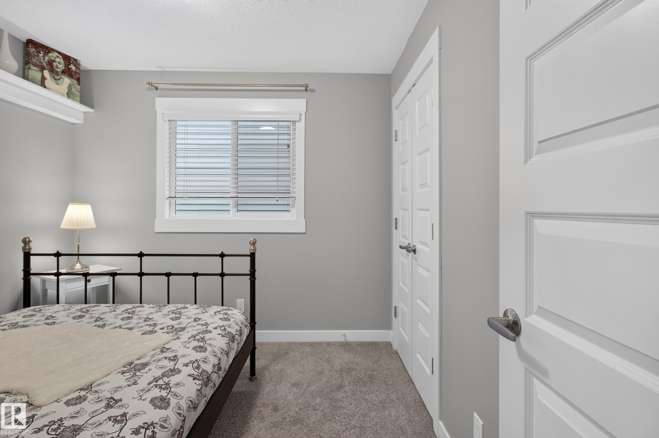 Bedroom featuring light gray walls, carpet flooring, a window with blinds, and a closet with bifold doors - 17305 73 Street Nw, Edmonton, AB - Indoor Photo Showing Bedroom
