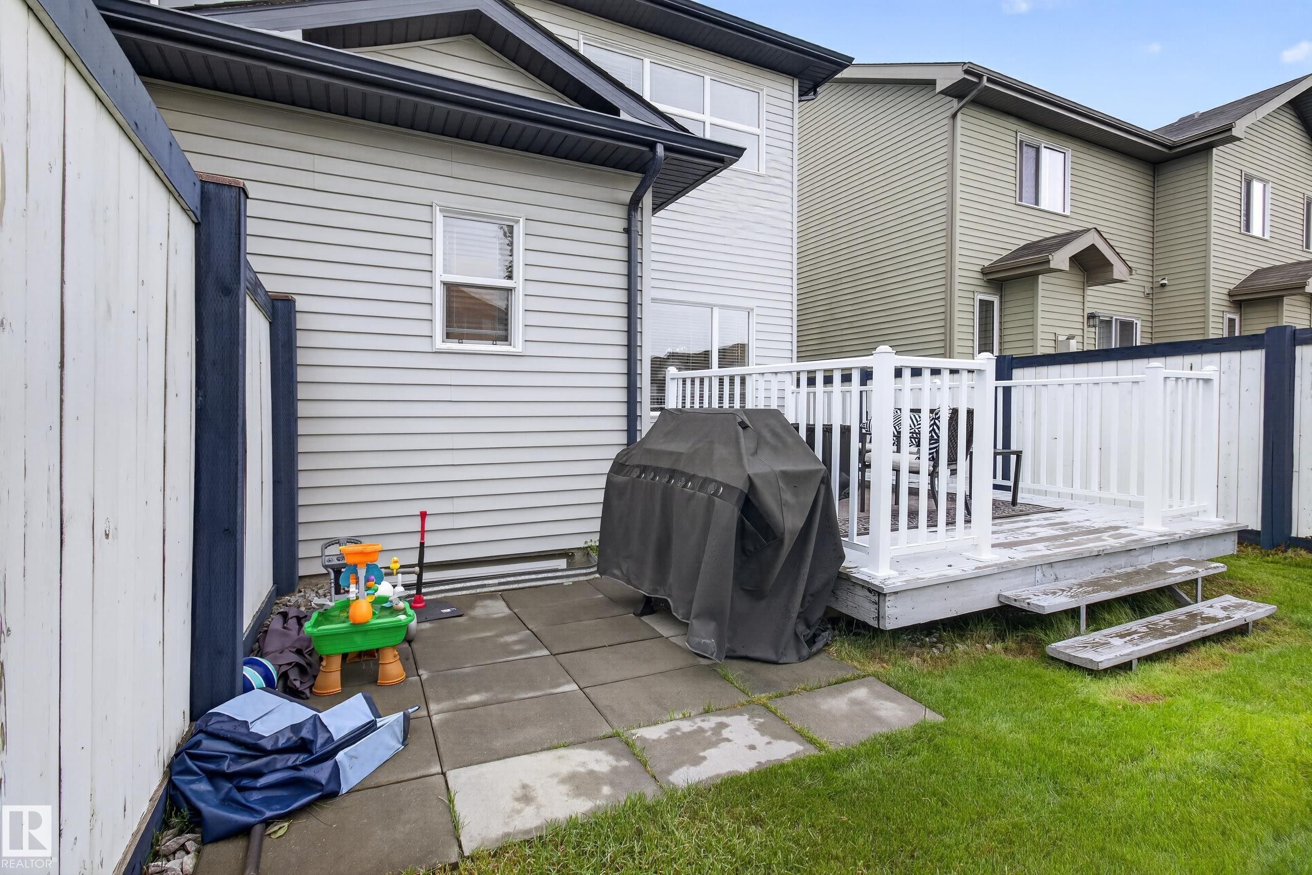 Private rear yard featuring a white wooden deck with railing, a paved patio area, and a grass lawn - 17305 73 Street Nw, Edmonton, AB - Outdoor With Deck Patio Veranda With Exterior