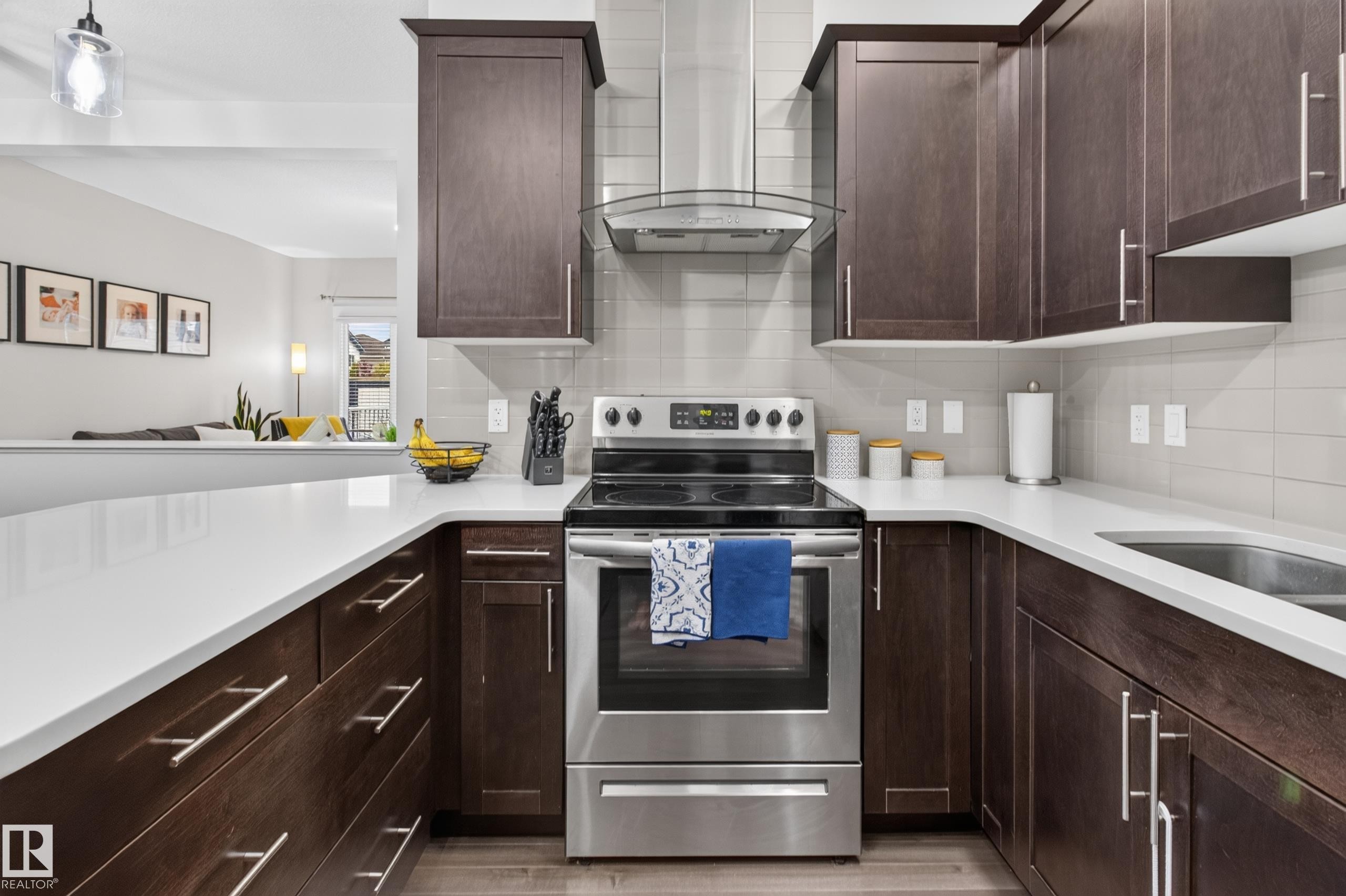 Modern kitchen featuring dark wood-finish cabinetry with brushed nickel hardware, white countertops, and a full suite of stainless steel appliances - 17305 73 Street Nw, Edmonton, AB - Indoor Photo Showing Kitchen With Stainless Steel Kitchen With Upgraded Kitchen