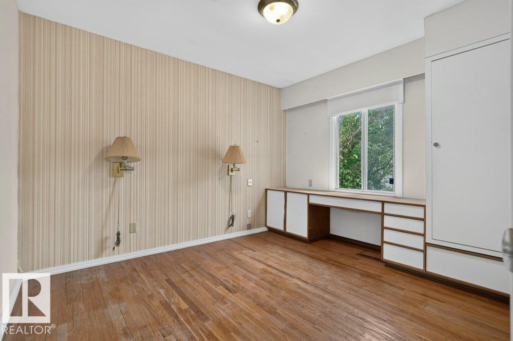 Wood-finish flooring with built-in desk and storage cabinetry - 9026 92 Street Nw, Edmonton, AB - Indoor