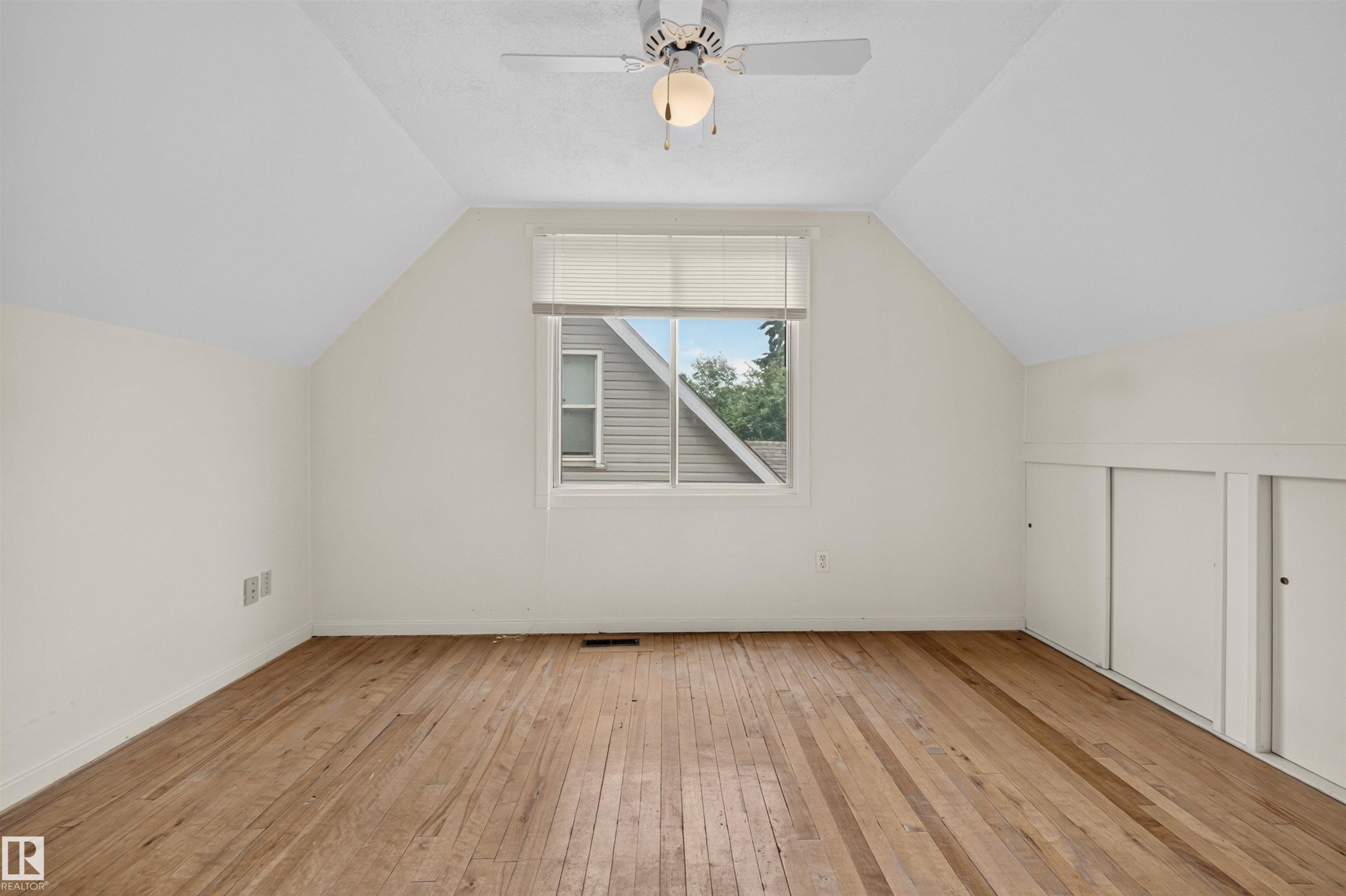Sloped ceilings, wood-finish flooring, a ceiling fan, a window, and built-in storage - 9026 92 Street Nw, Edmonton, AB - Indoor Photo Showing Other Room
