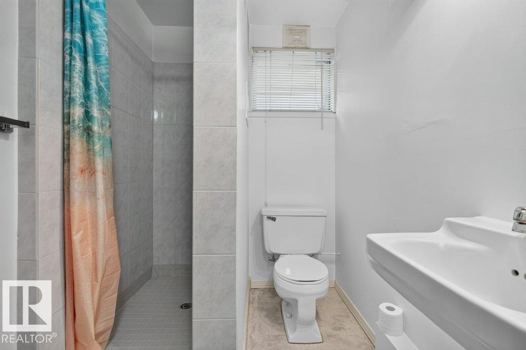 Tiled shower stall, white pedestal sink, and white toilet - 9026 92 Street Nw, Edmonton, AB - Indoor Photo Showing Bathroom