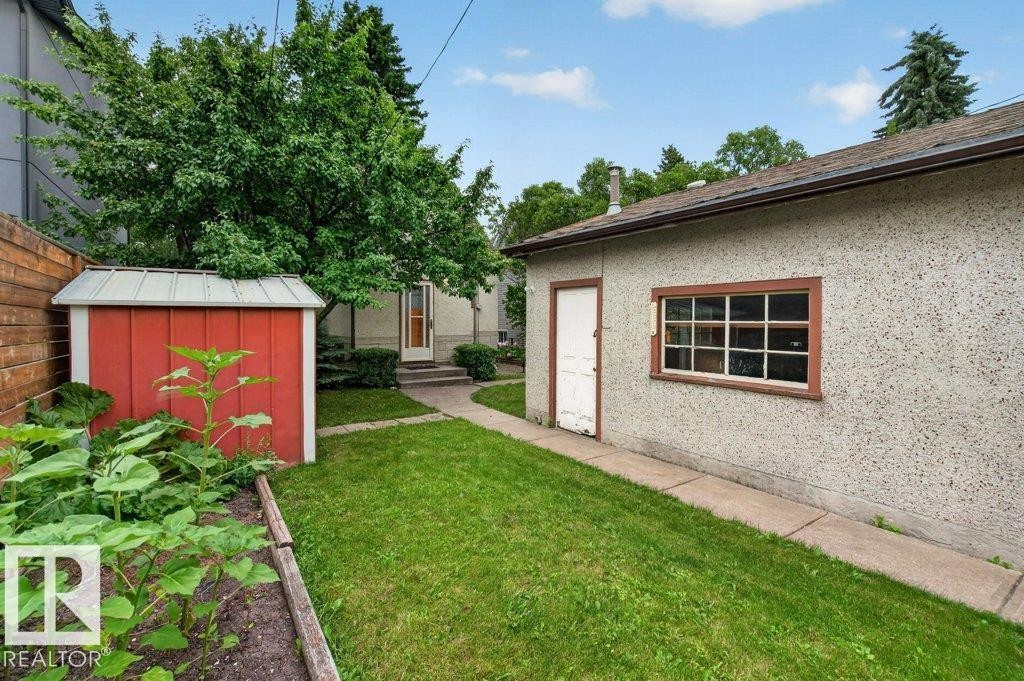 Expansive backyard featuring a manicured lawn, red storage shed, and mature trees - 9026 92 Street Nw, Edmonton, AB - Outdoor