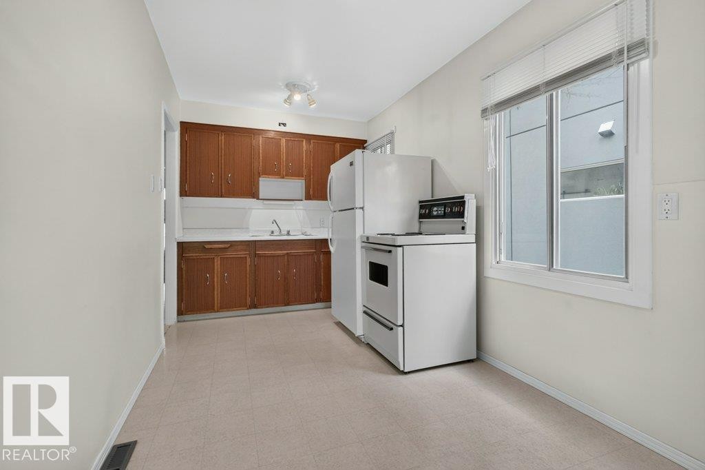 Kitchen with wood-finish cabinetry, white countertops, and vinyl flooring - 9026 92 Street Nw, Edmonton, AB - Indoor Photo Showing Kitchen