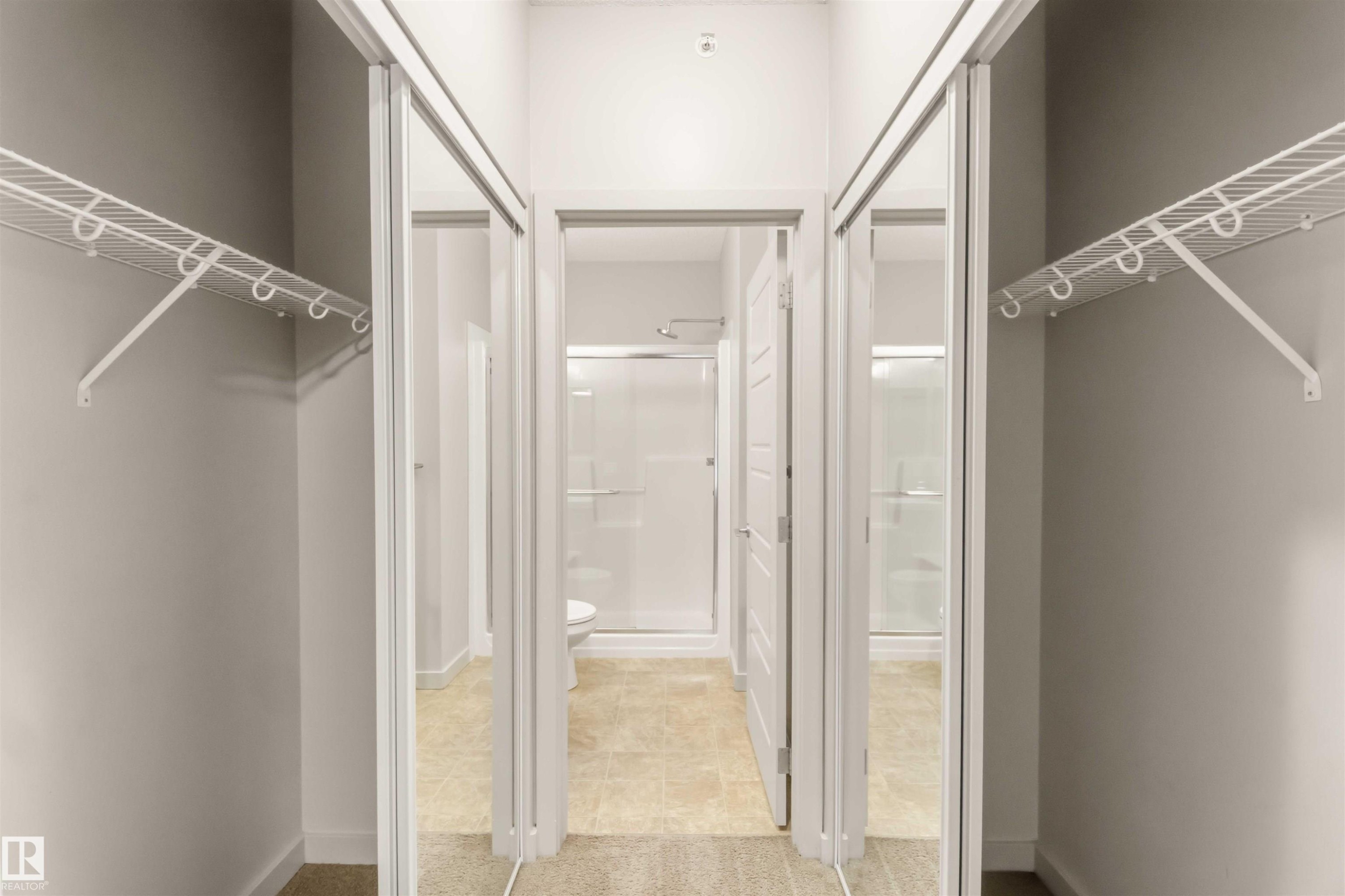 Sliding mirrored doors, white wire shelving, light-toned flooring, and a shower enclosure - #414 5510 Schonsee Dr Nw, Edmonton, AB