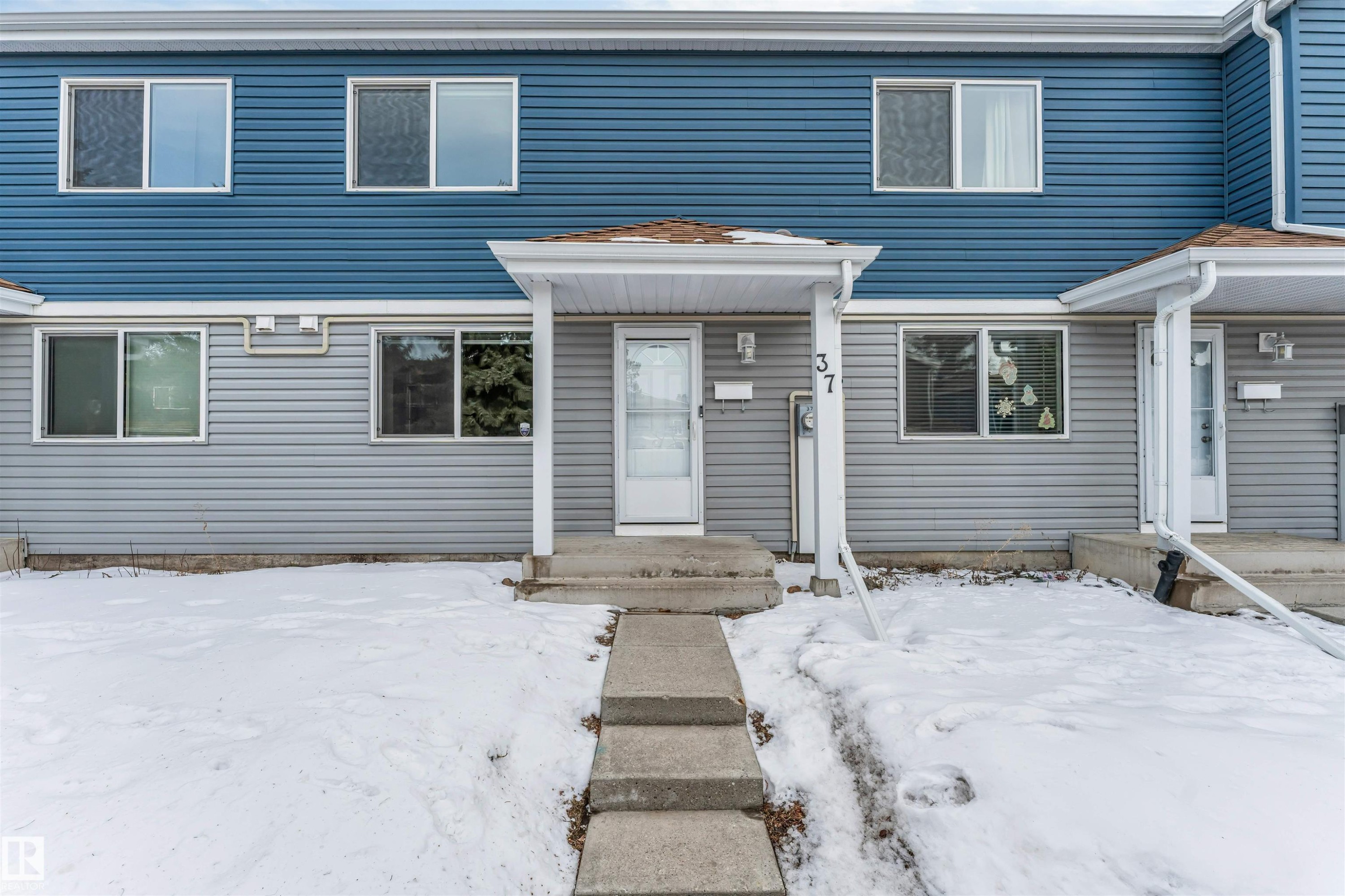 Two-story exterior with blue and gray horizontal siding, an entry porch, and a concrete walkway - #37 1411 Mill Woods Rd E Nw, Edmonton, AB - Outdoor