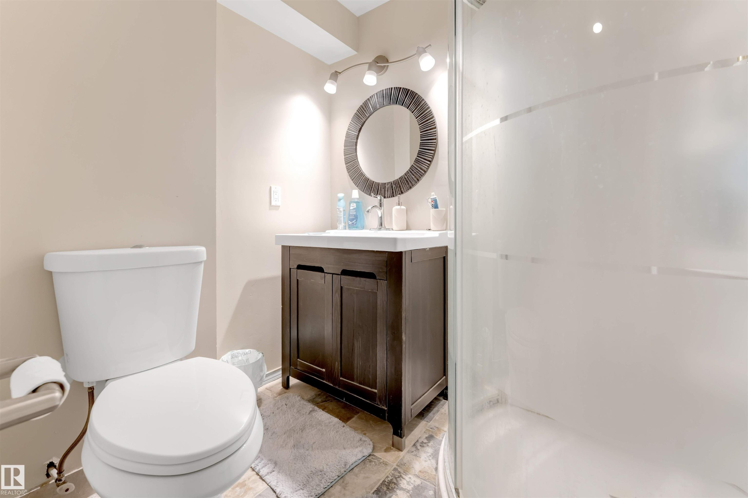 Dark wood-finish vanity with an integrated sink, illuminated by a track light fixture - #37 1411 Mill Woods Rd E Nw, Edmonton, AB - Indoor Photo Showing Bathroom