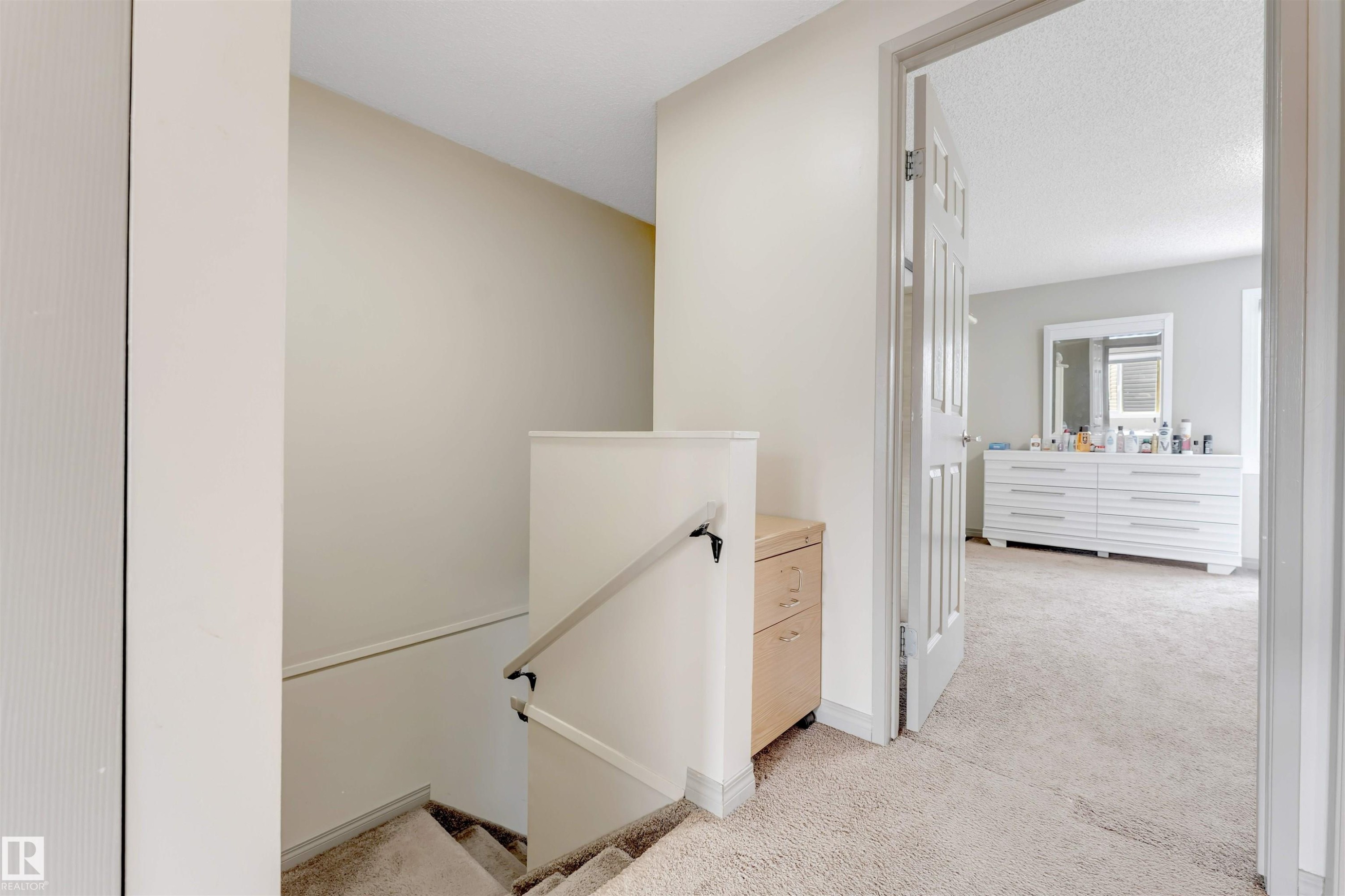 Carpeted flooring extending through a doorway, with a wood-finish cabinet built into the wall - #37 1411 Mill Woods Rd E Nw, Edmonton, AB - Indoor Photo Showing Other Room