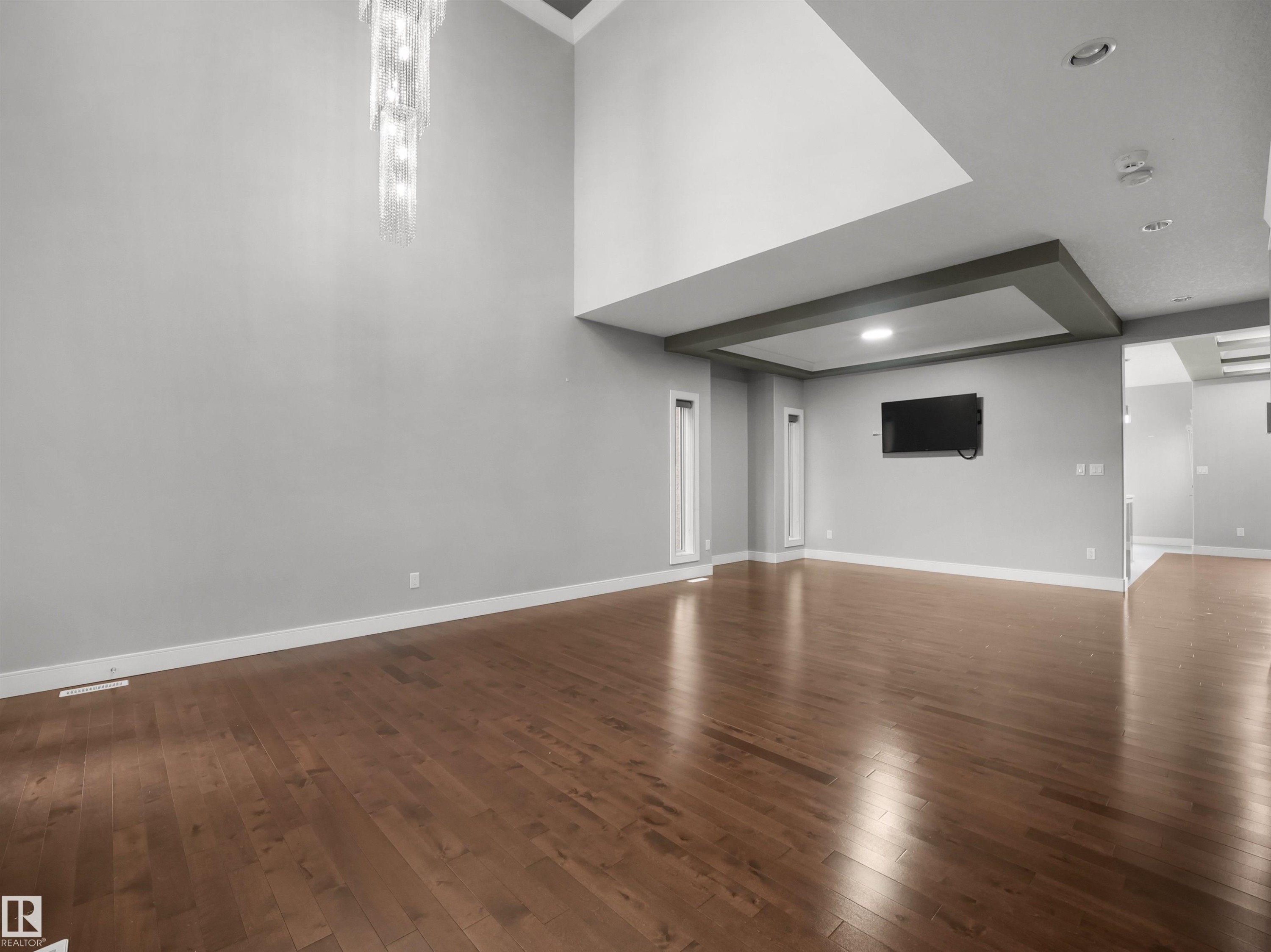 Vaulted ceiling with a contemporary chandelier, recessed lighting, wood-finish flooring, and a decorative ceiling beam accent - 17020 62 Street Nw, Edmonton, AB - Indoor Photo Showing Other Room