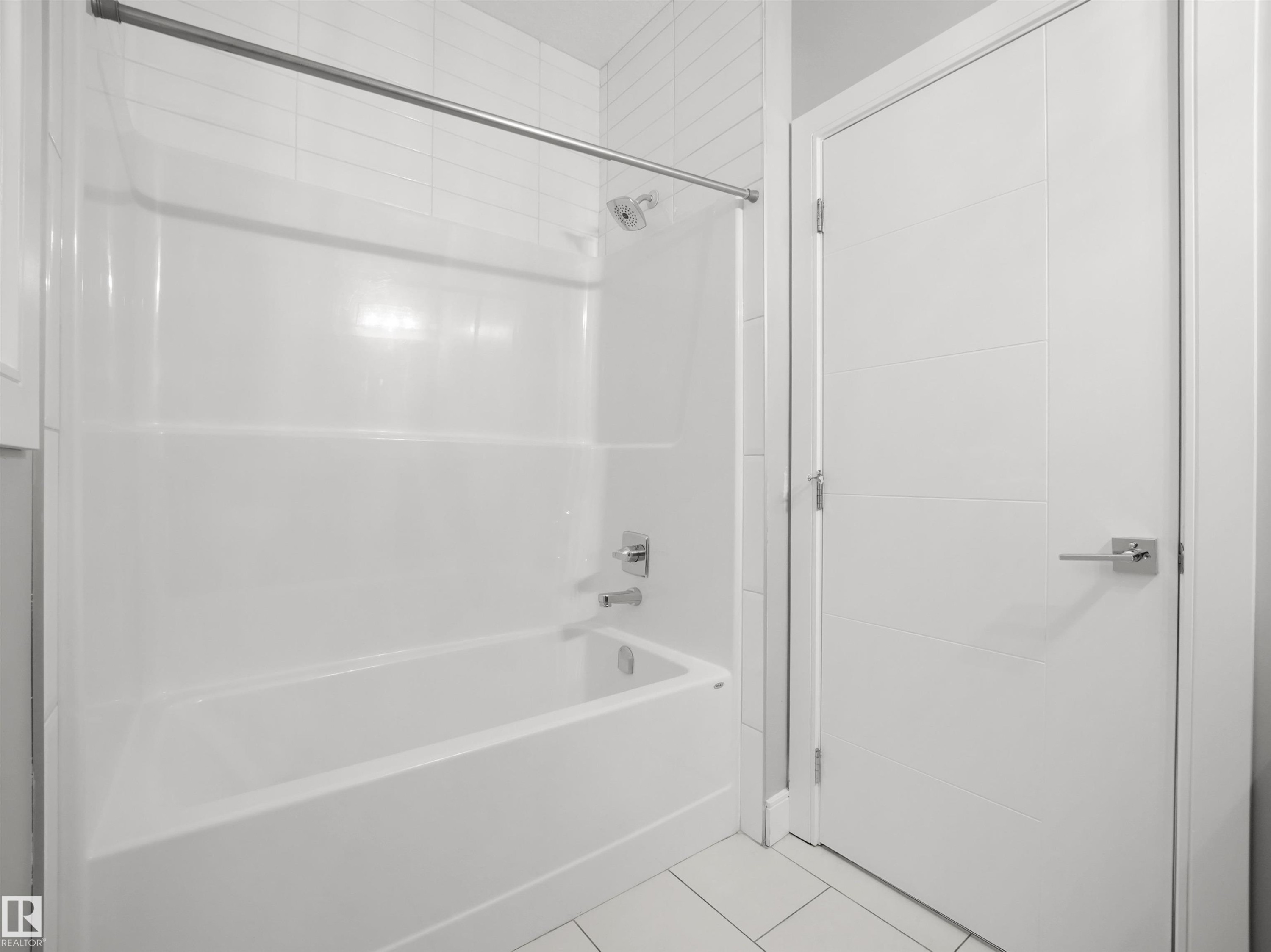 Tub and shower combination with chrome fixtures, subway tile surround, and a modern paneled door - 17020 62 Street Nw, Edmonton, AB - Indoor Photo Showing Bathroom