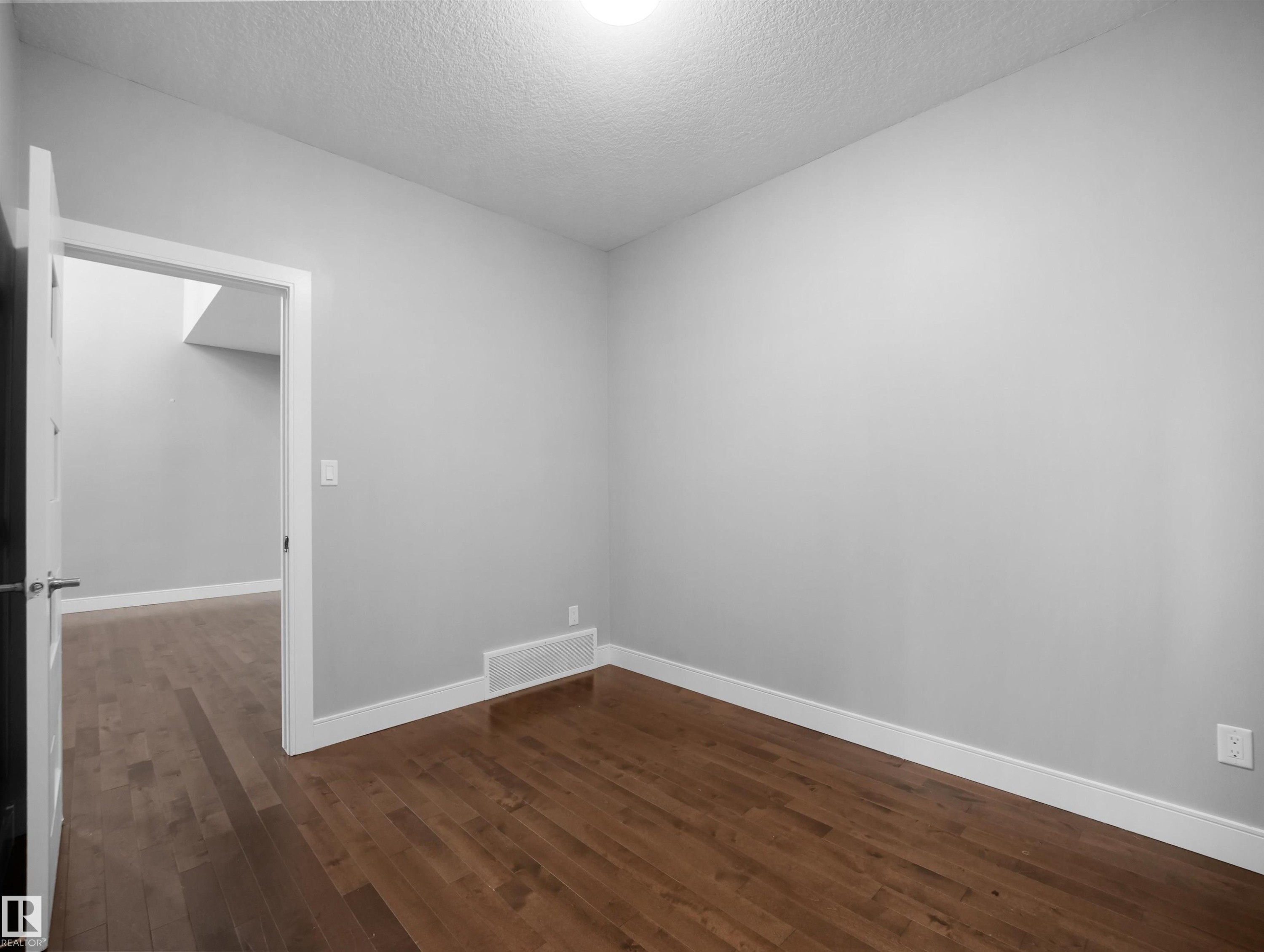 Wood-finish flooring with white trim and a neutral wall color - 17020 62 Street Nw, Edmonton, AB - Indoor Photo Showing Other Room