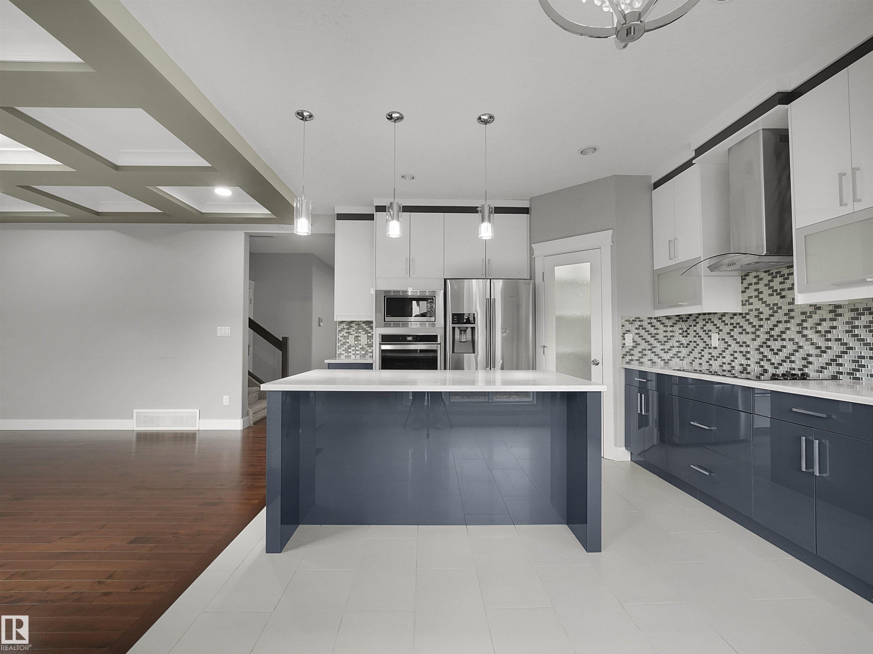 Modern kitchen featuring a large central island, stainless steel appliances, a geometric tile backsplash, and two-tone cabinetry - 17020 62 Street Nw, Edmonton, AB - Indoor Photo Showing Kitchen With Upgraded Kitchen