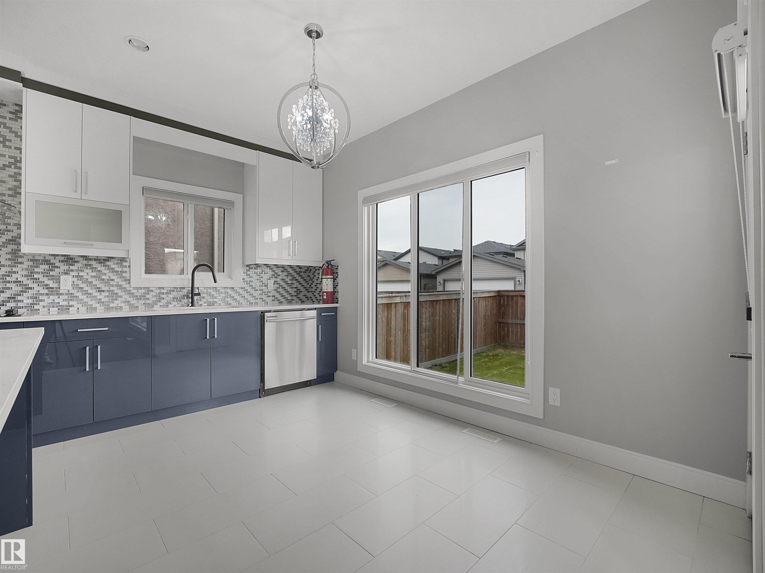 Contemporary kitchen featuring white and navy cabinetry, a mosaic tile backsplash, a stainless steel dishwasher, and a black faucet - 17020 62 Street Nw, Edmonton, AB - Indoor Photo Showing Kitchen With Upgraded Kitchen