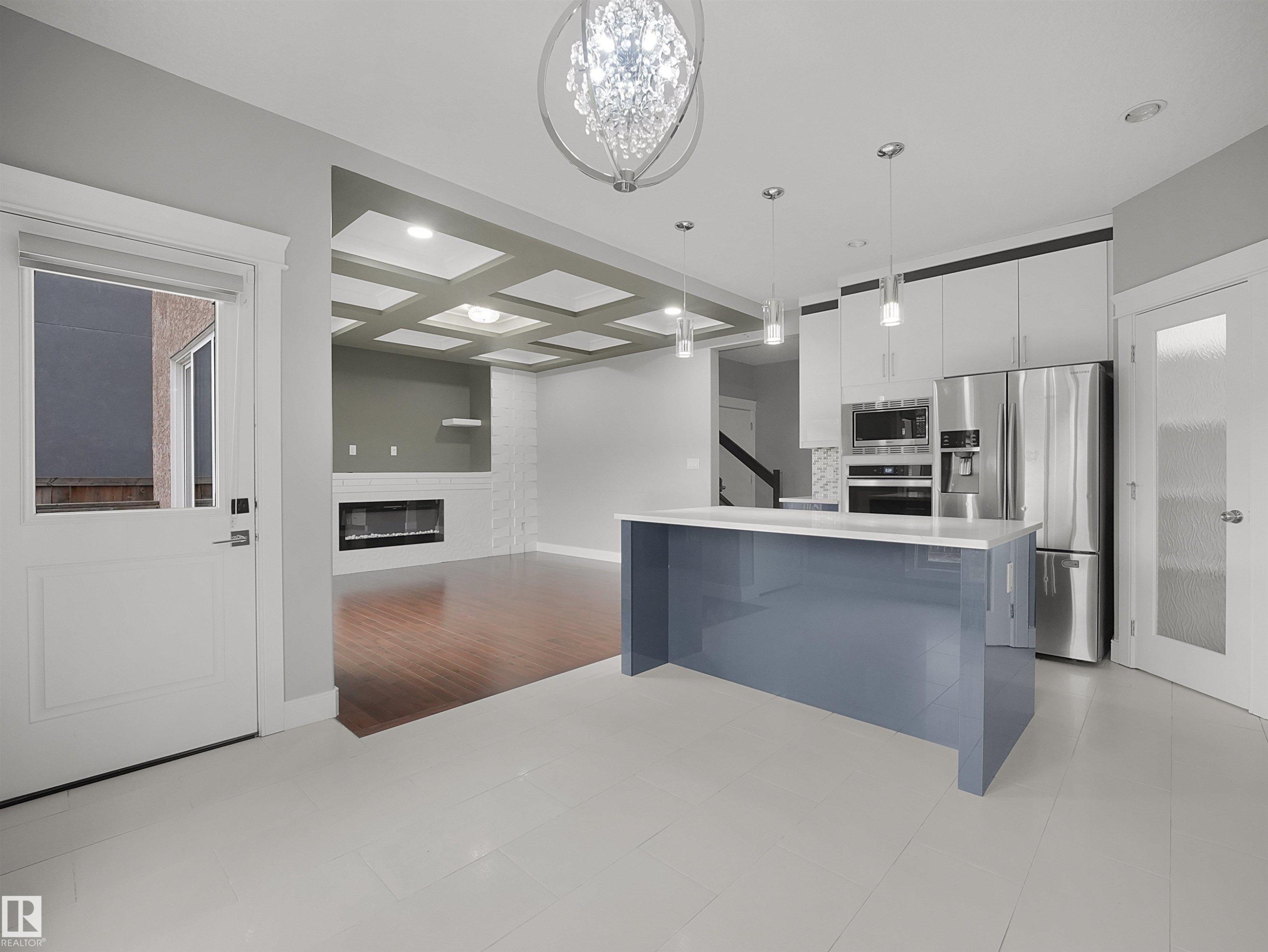 Kitchen island with a light blue finish and white countertop, stainless steel appliances, pendant lighting, wood-finish flooring, and a coffered ceiling - 17020 62 Street Nw, Edmonton, AB - Indoor Photo Showing Kitchen