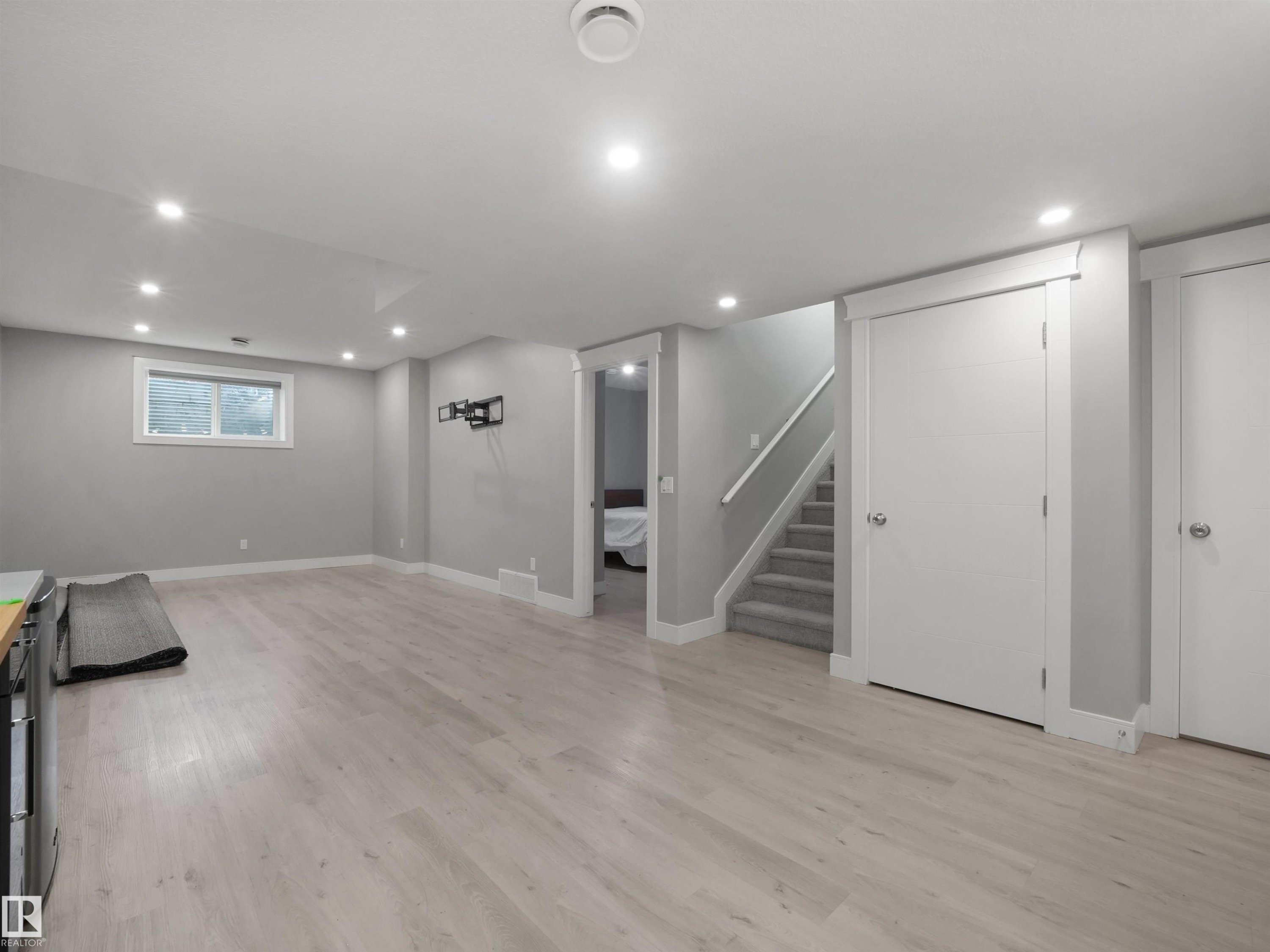 Recessed lighting, wood-finish flooring, light gray wall paint, white trim, and a carpeted staircase - 17020 62 Street Nw, Edmonton, AB - Indoor Photo Showing Other Room