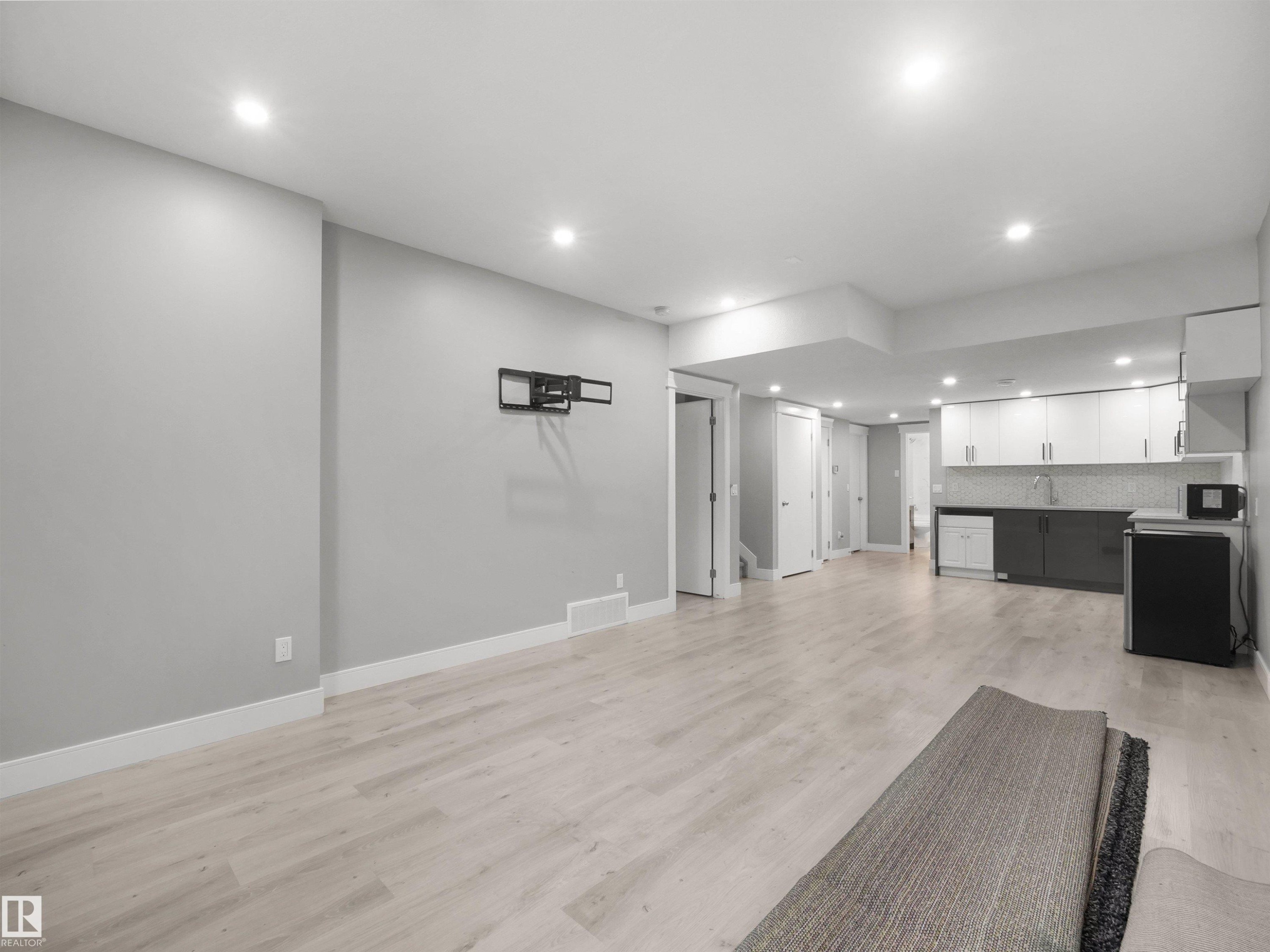 Recessed lighting, wood-finish flooring, and a kitchen area with light and dark cabinetry and a tile backsplash - 17020 62 Street Nw, Edmonton, AB - Indoor