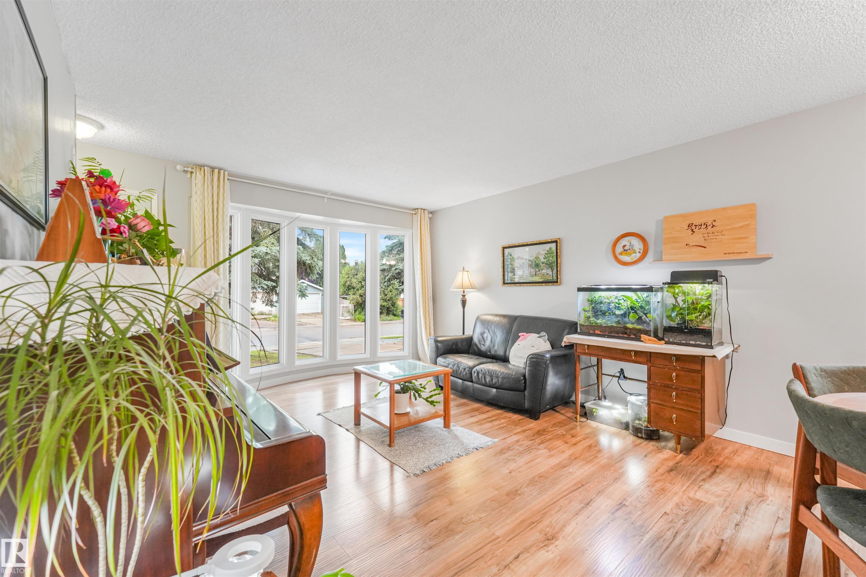 Living area featuring wood-finish flooring, light gray wall paint, and a bay window with multiple panes - 18611 57 Avenue Nw, Edmonton, AB - Indoor Photo Showing Living Room
