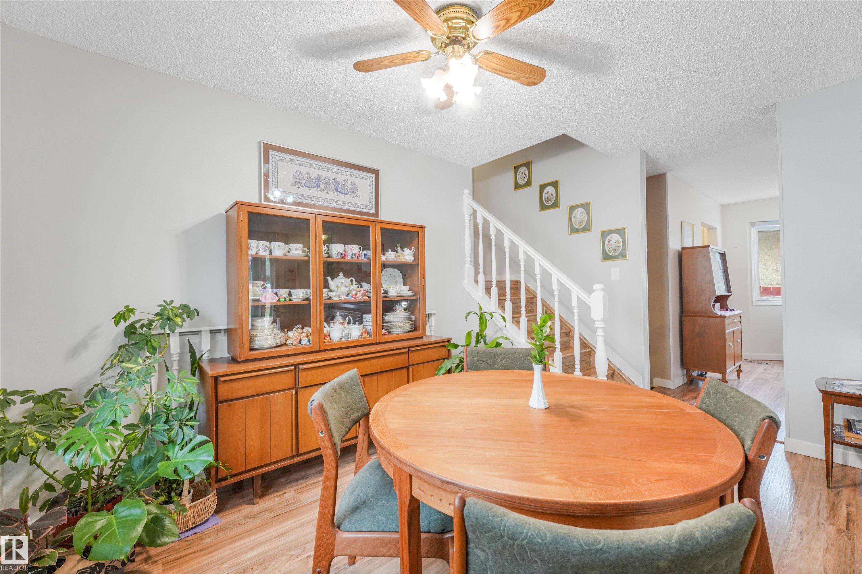 Dining area featuring wood-finish flooring, a white spindle staircase, and a ceiling fan with integrated lighting - 18611 57 Avenue Nw, Edmonton, AB - Indoor Photo Showing Dining Room