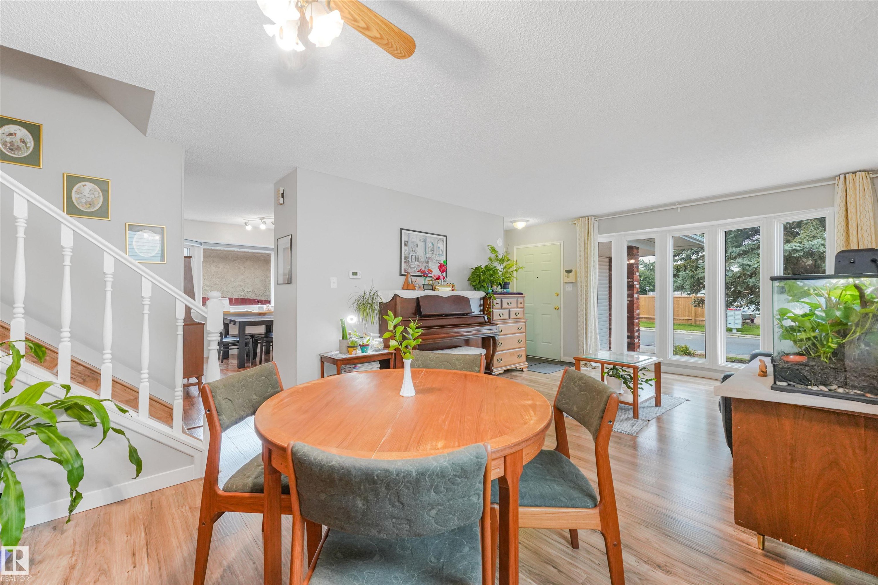 Open-concept living area featuring wood-finish flooring, a white staircase with balusters, and a ceiling fan with light fixture - 18611 57 Avenue Nw, Edmonton, AB - Indoor Photo Showing Dining Room