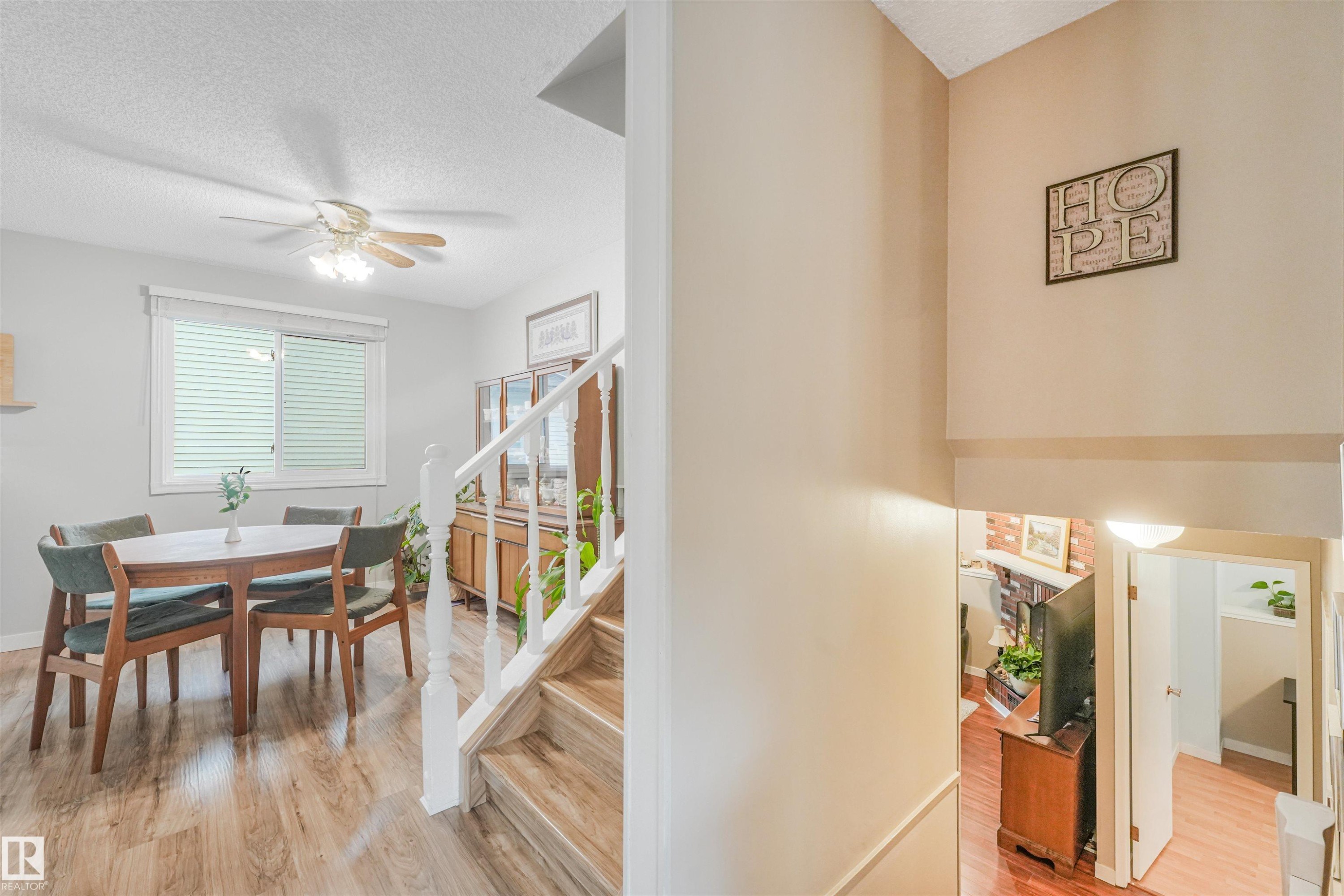 Open-concept dining area featuring wood-finish flooring, a ceiling fan with light fixture, and a window with blinds - 18611 57 Avenue Nw, Edmonton, AB - Indoor Photo Showing Dining Room
