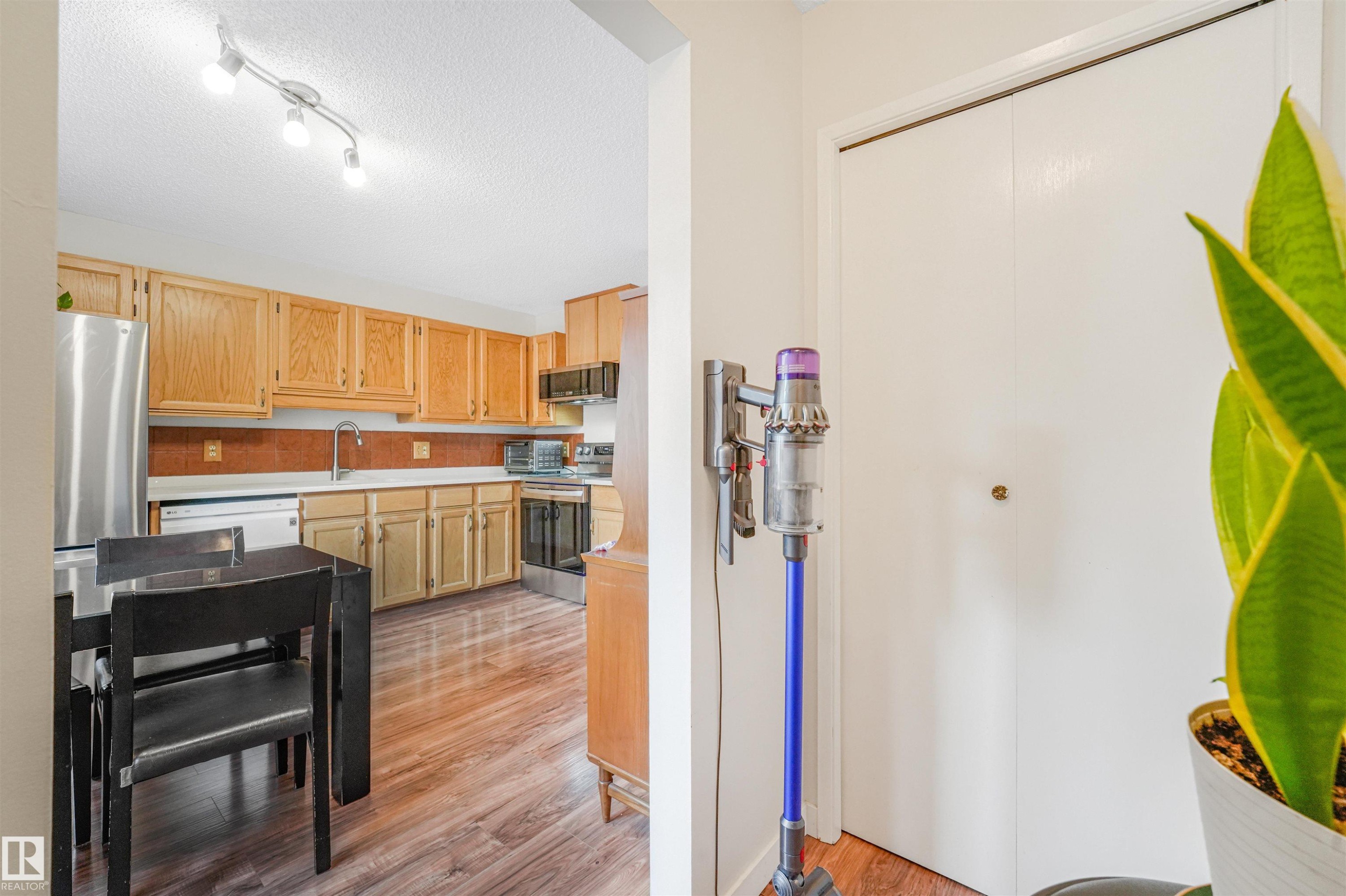 Kitchen featuring wood-finish flooring, stainless steel refrigerator, white dishwasher, and natural wood cabinetry - 18611 57 Avenue Nw, Edmonton, AB - Indoor Photo Showing Other Room