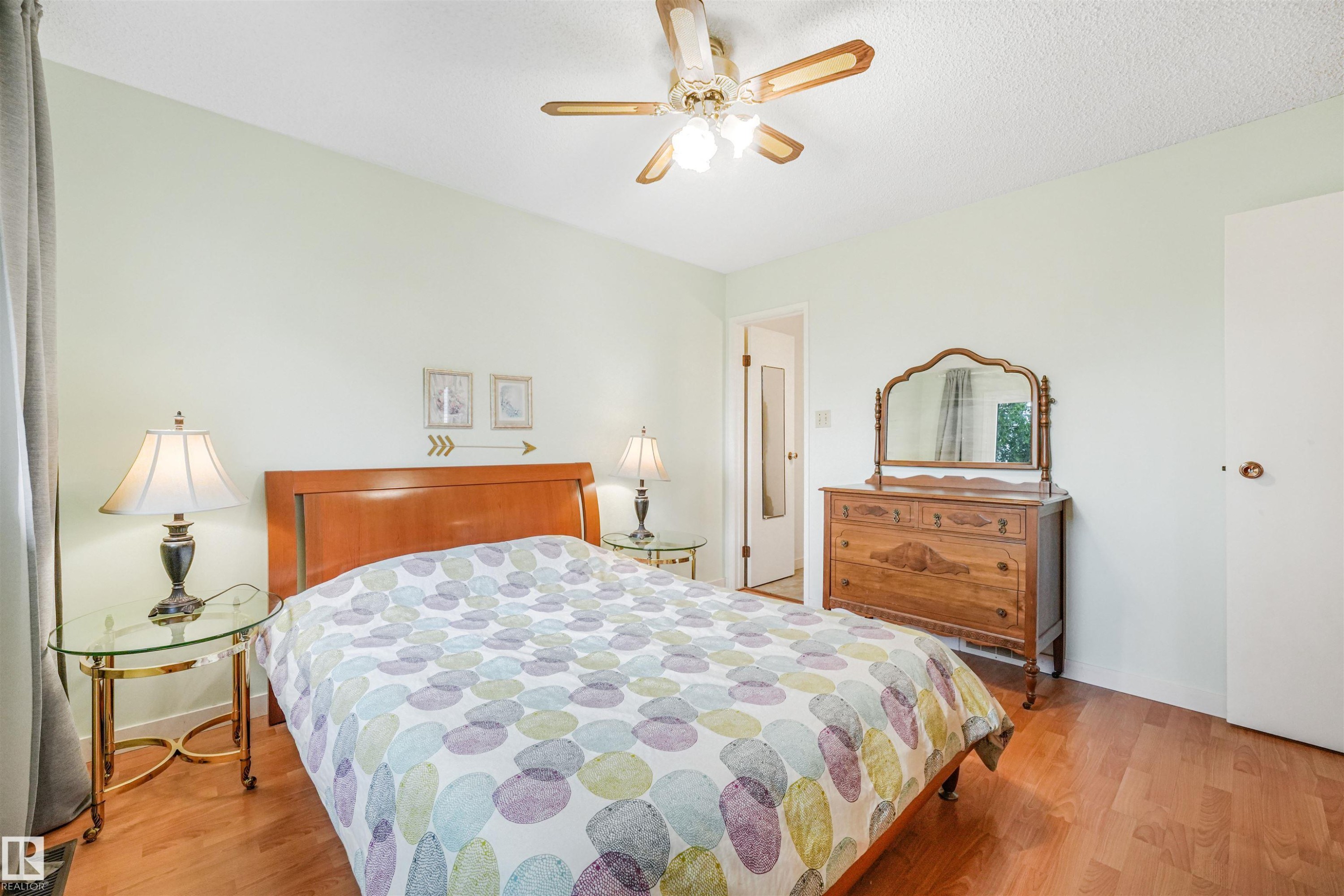 Bright bedroom featuring wood-finish flooring and a ceiling fan with integrated lighting - 18611 57 Avenue Nw, Edmonton, AB - Indoor Photo Showing Bedroom