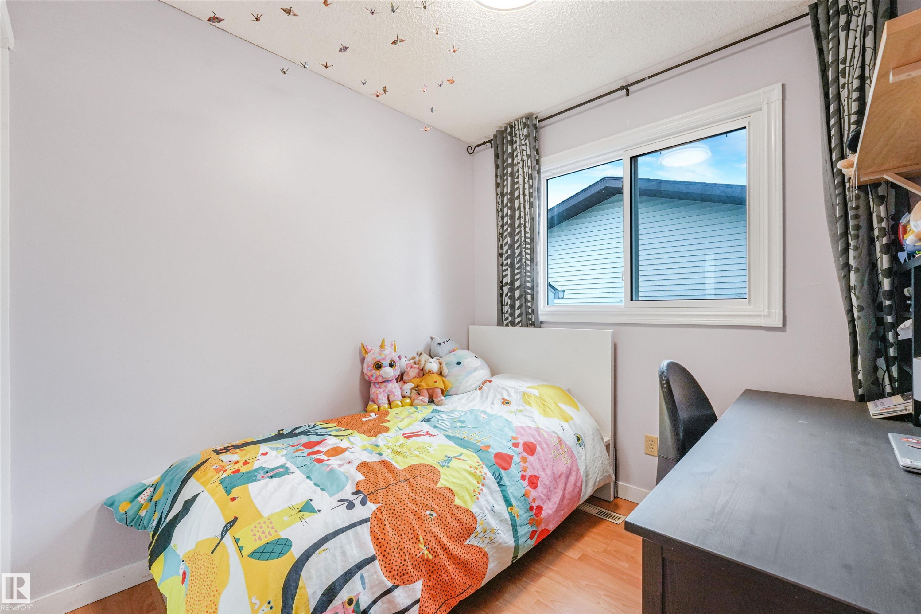 Light-filled room featuring wood-finish flooring, a white-framed window, and a ceiling light fixture - 18611 57 Avenue Nw, Edmonton, AB - Indoor Photo Showing Bedroom